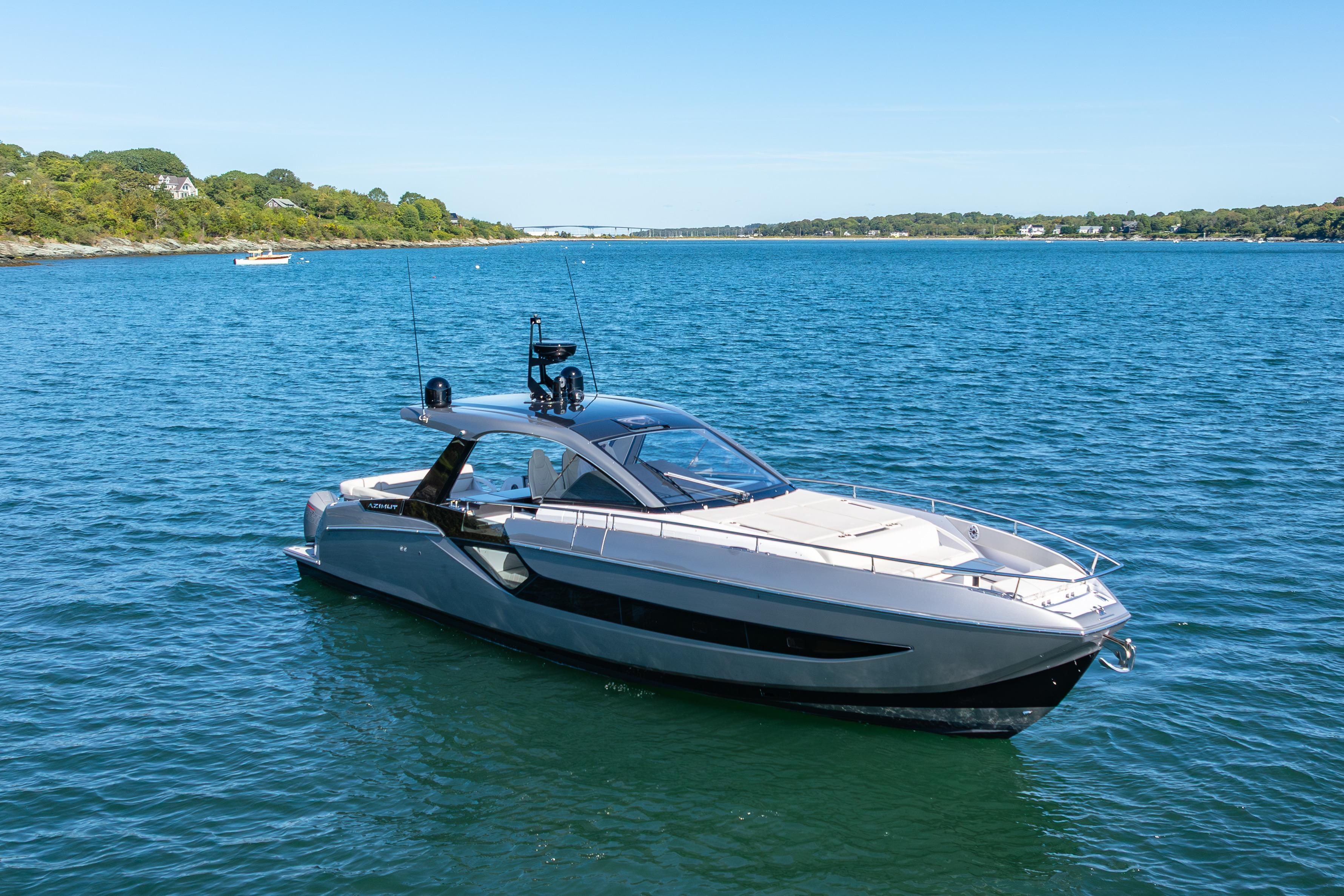 2023 Azimut Verve 47 yacht cruising on a serene blue lake under a clear sky.