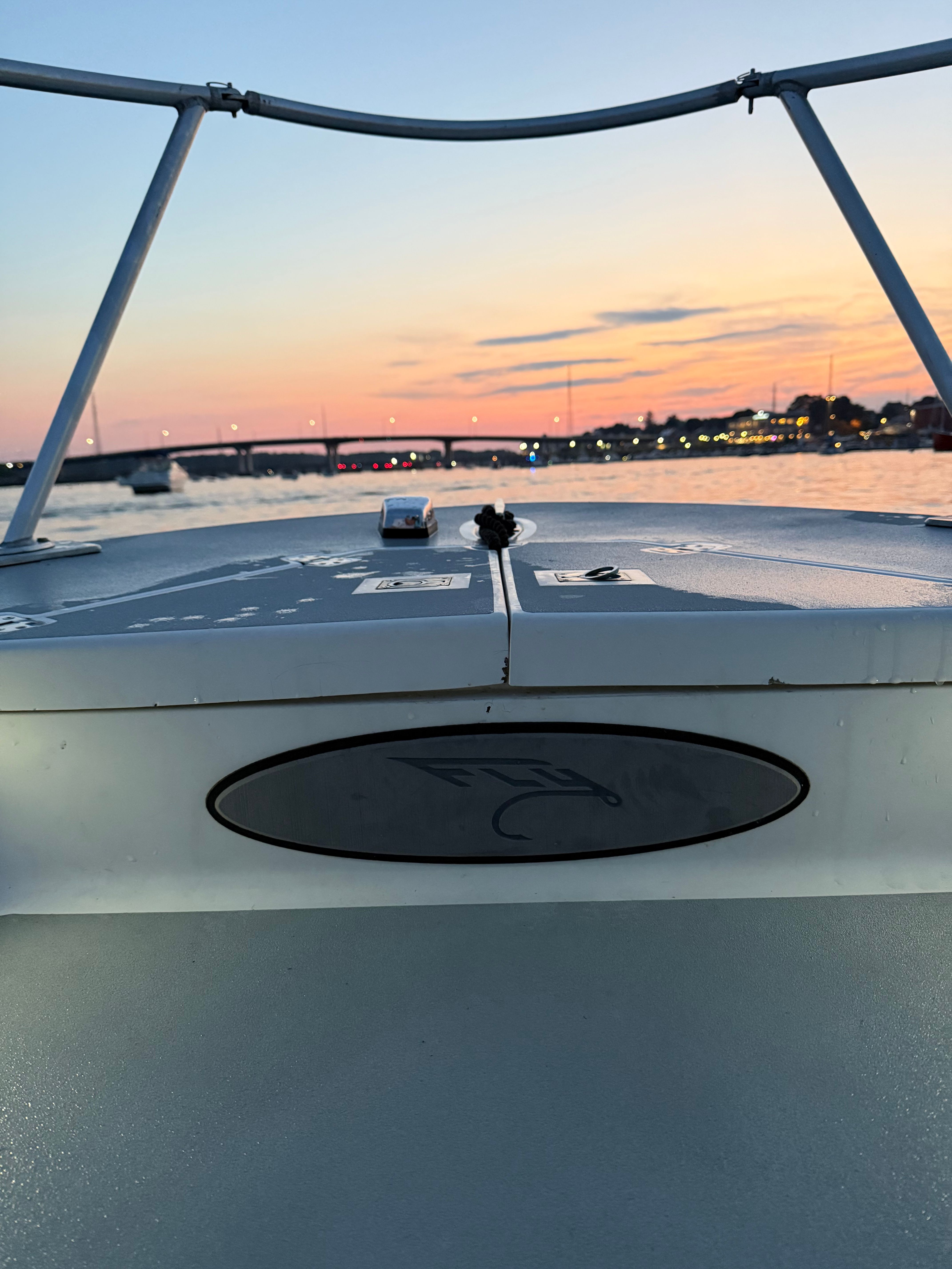 Custom Sea Fly 2004 boat at sunset, with bridge and city lights in background.