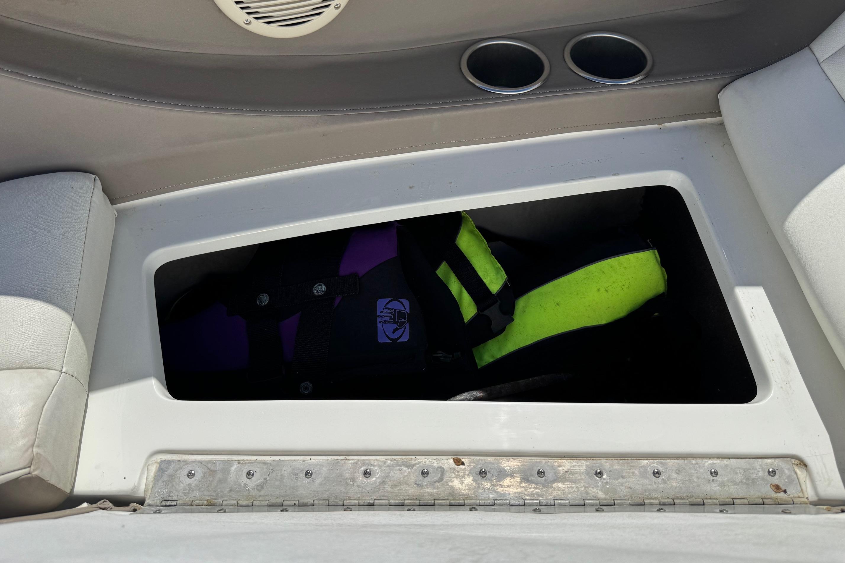 Storage compartment in a 2005 Cobalt 240 boat with life jackets inside.