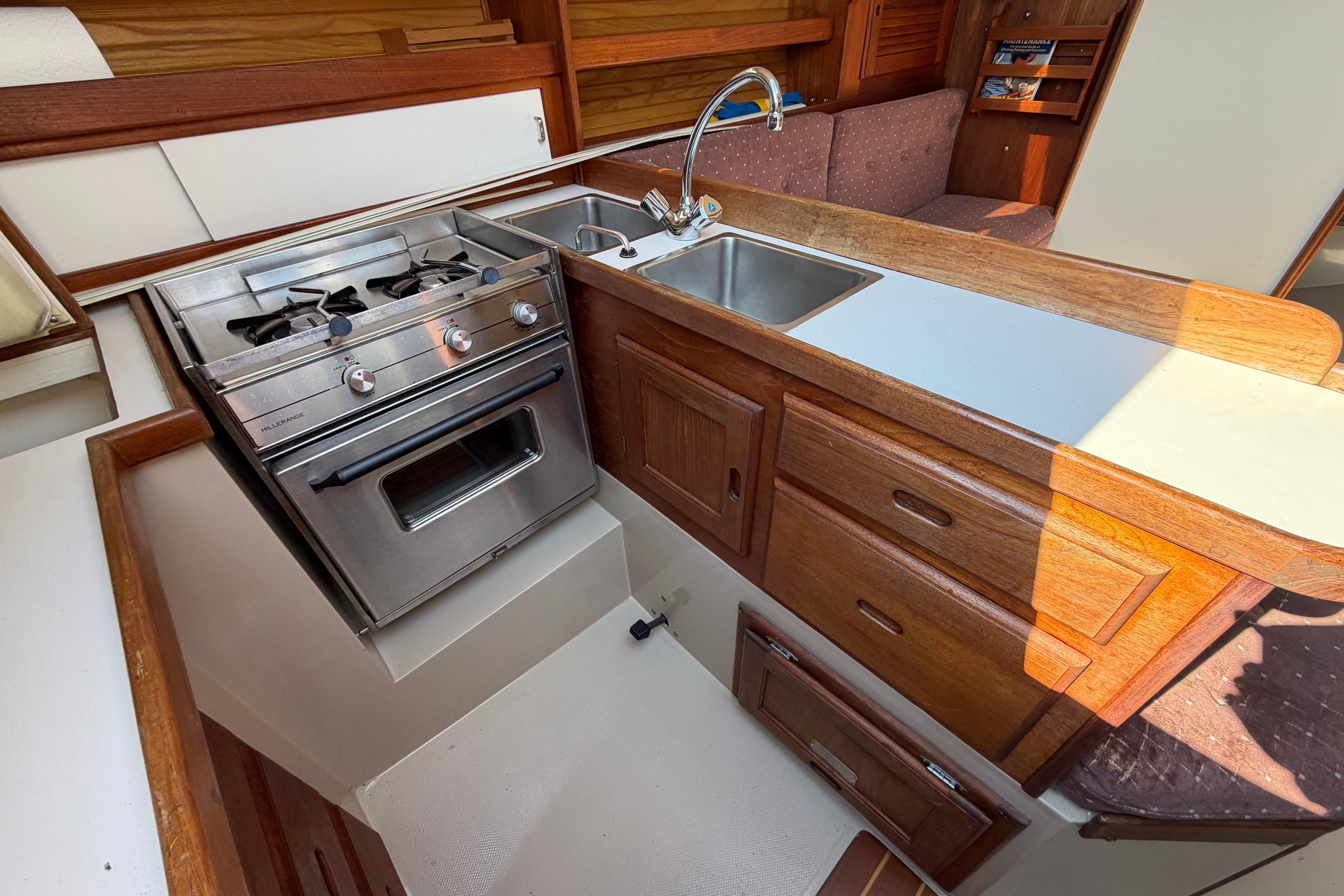 Galley kitchen in 1988 Catalina 30 MkII sailboat with stove, sink, and wooden cabinetry.