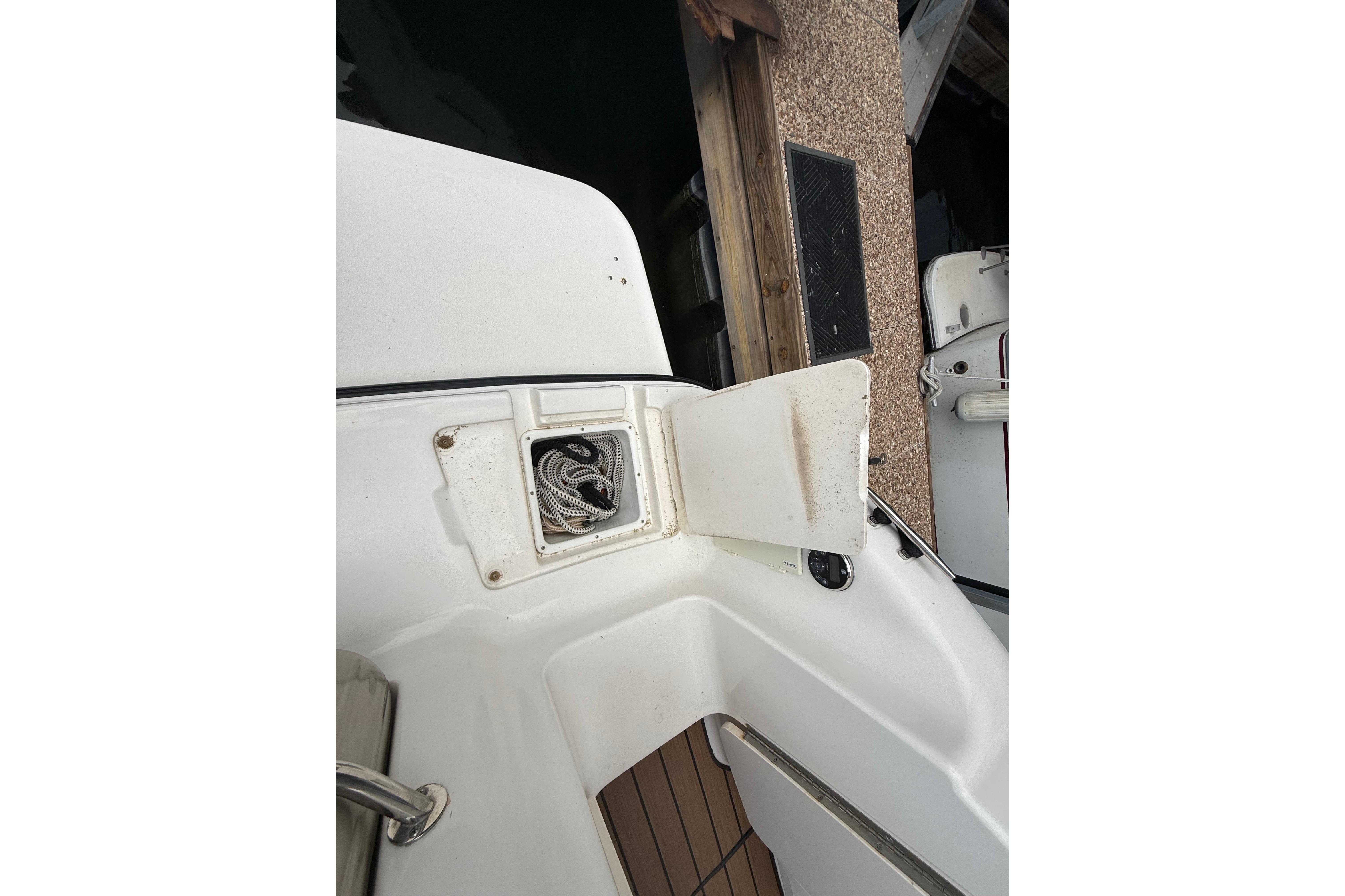 1999 Chaparral Signature 300 boat with open storage compartment near dock.