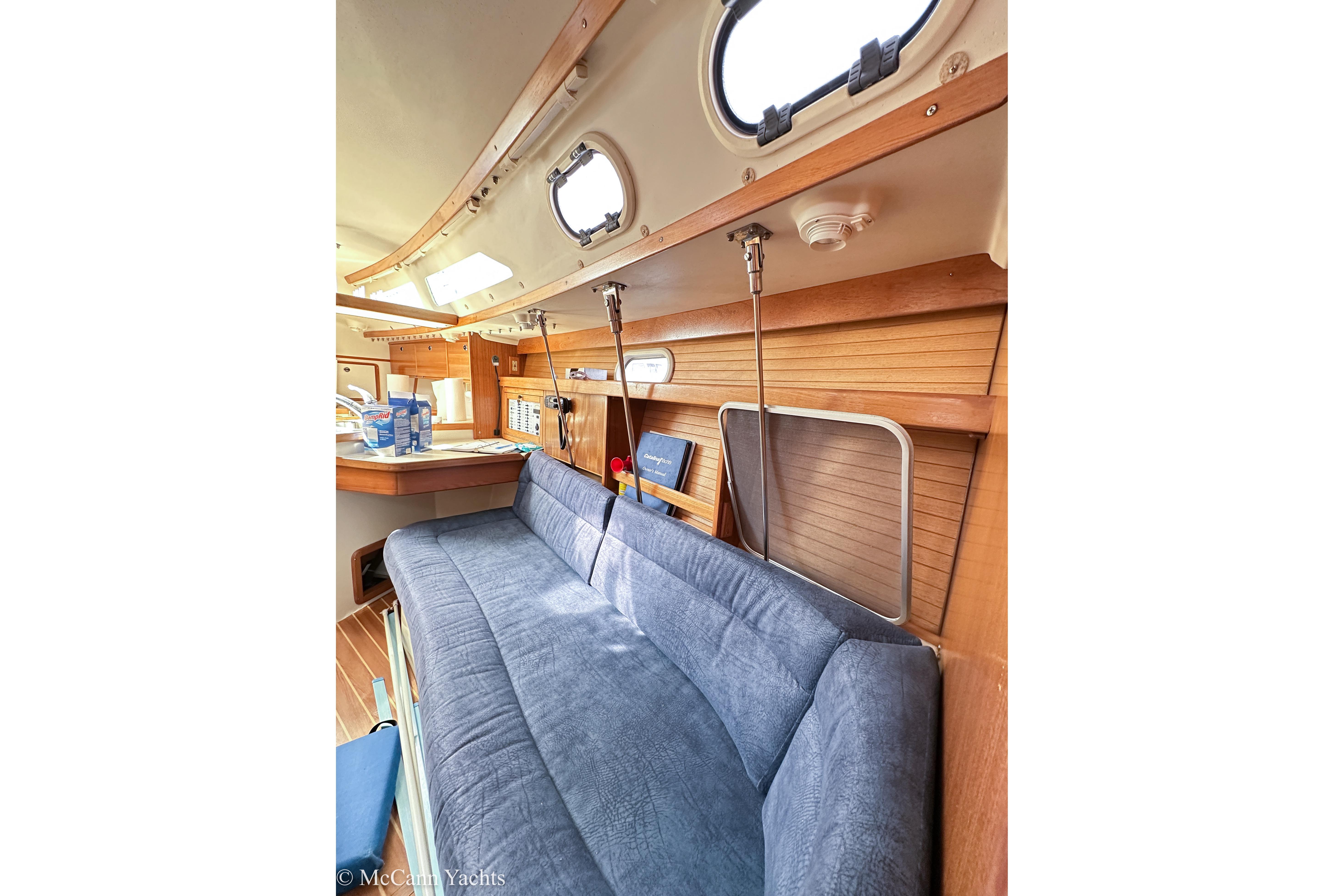 Interior of 2003 Catalina 320 yacht with blue sofa and wooden accents.