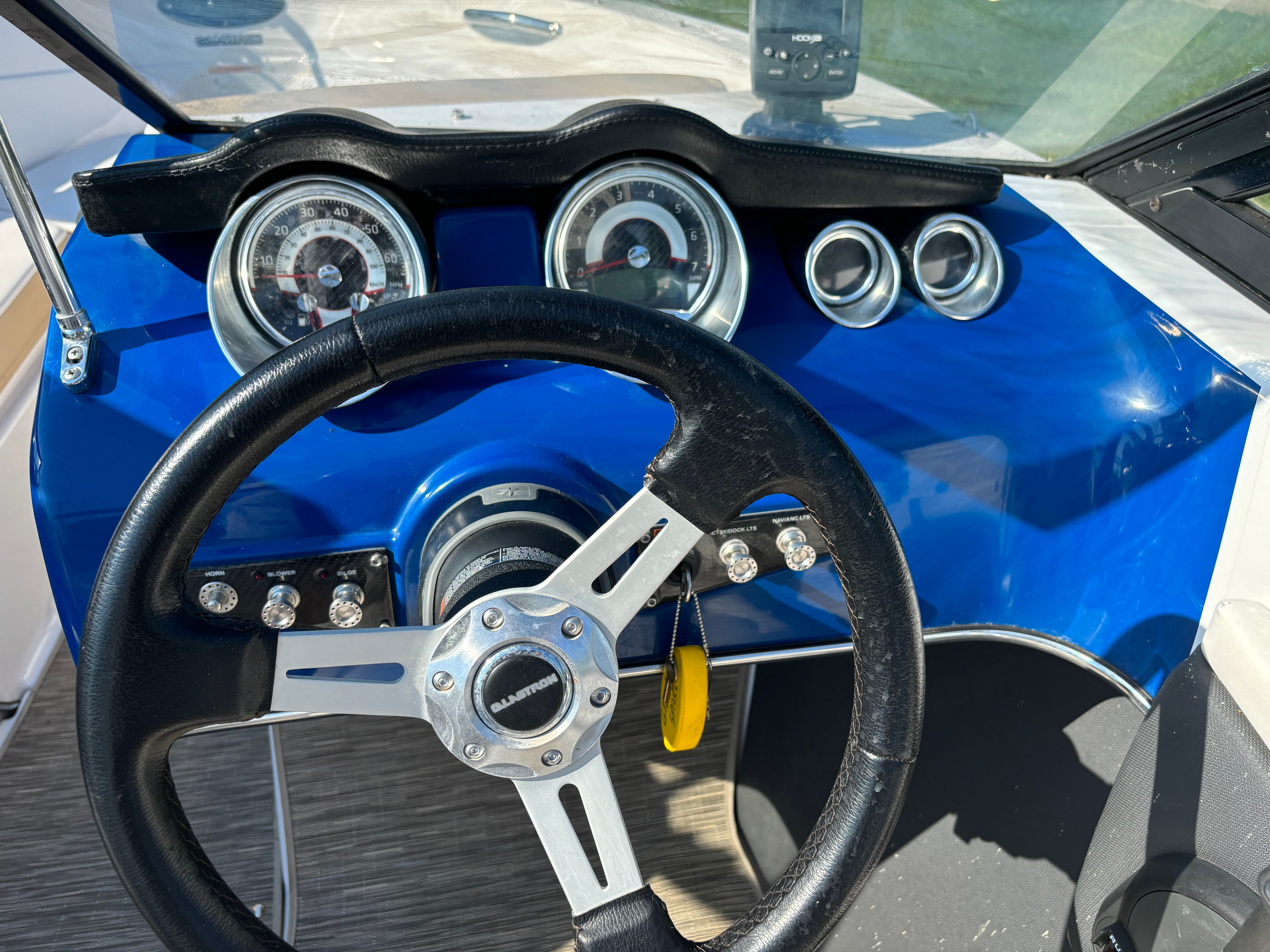 Close-up of a boat steering wheel and dashboard with blue paneling and instruments.