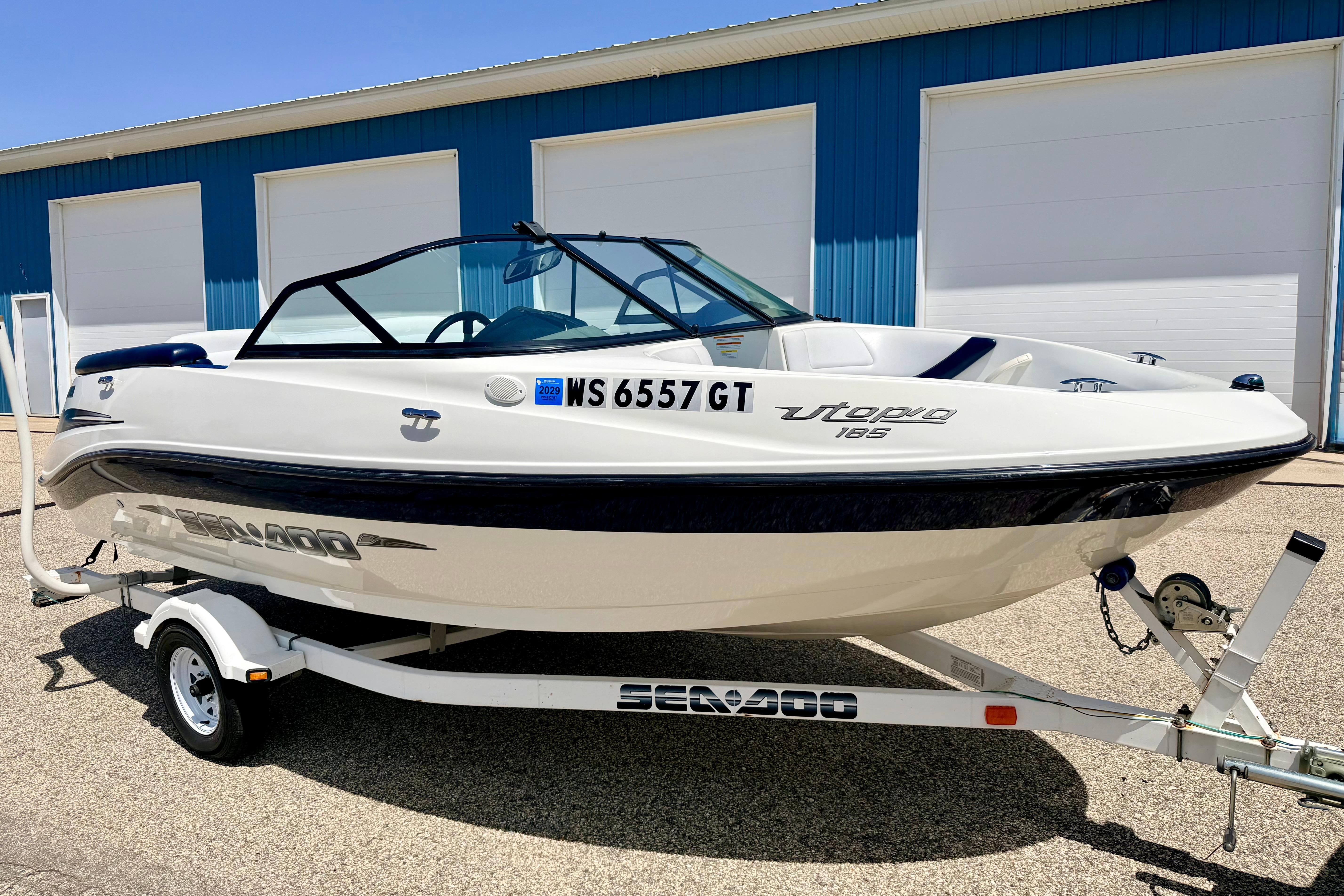 2004 Bombardier SEADOO Utopia 185 boat on trailer, parked outside blue building.