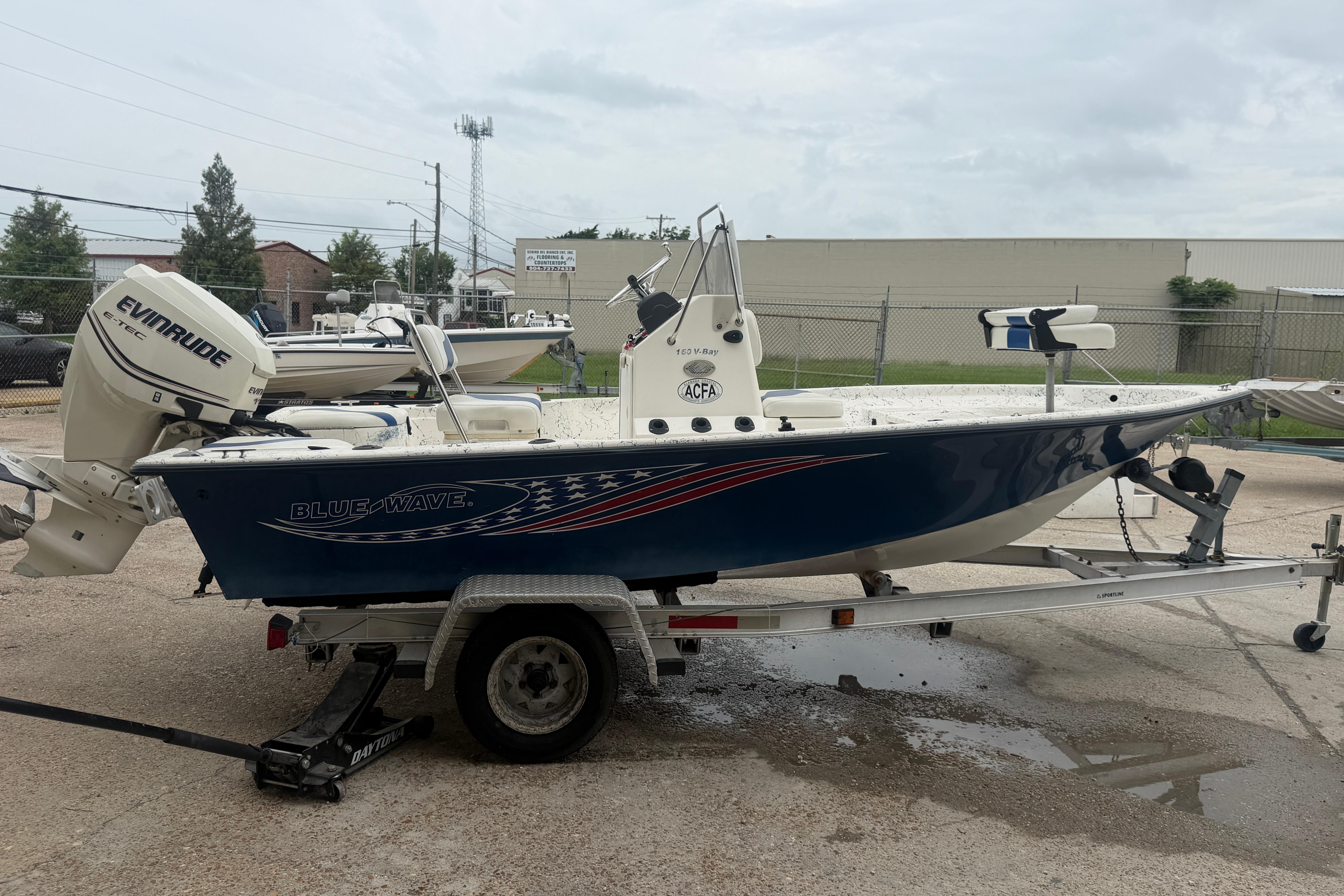 2004 Blue Wave 160 V-Bay boat on trailer with Evinrude motor, parked outdoors.