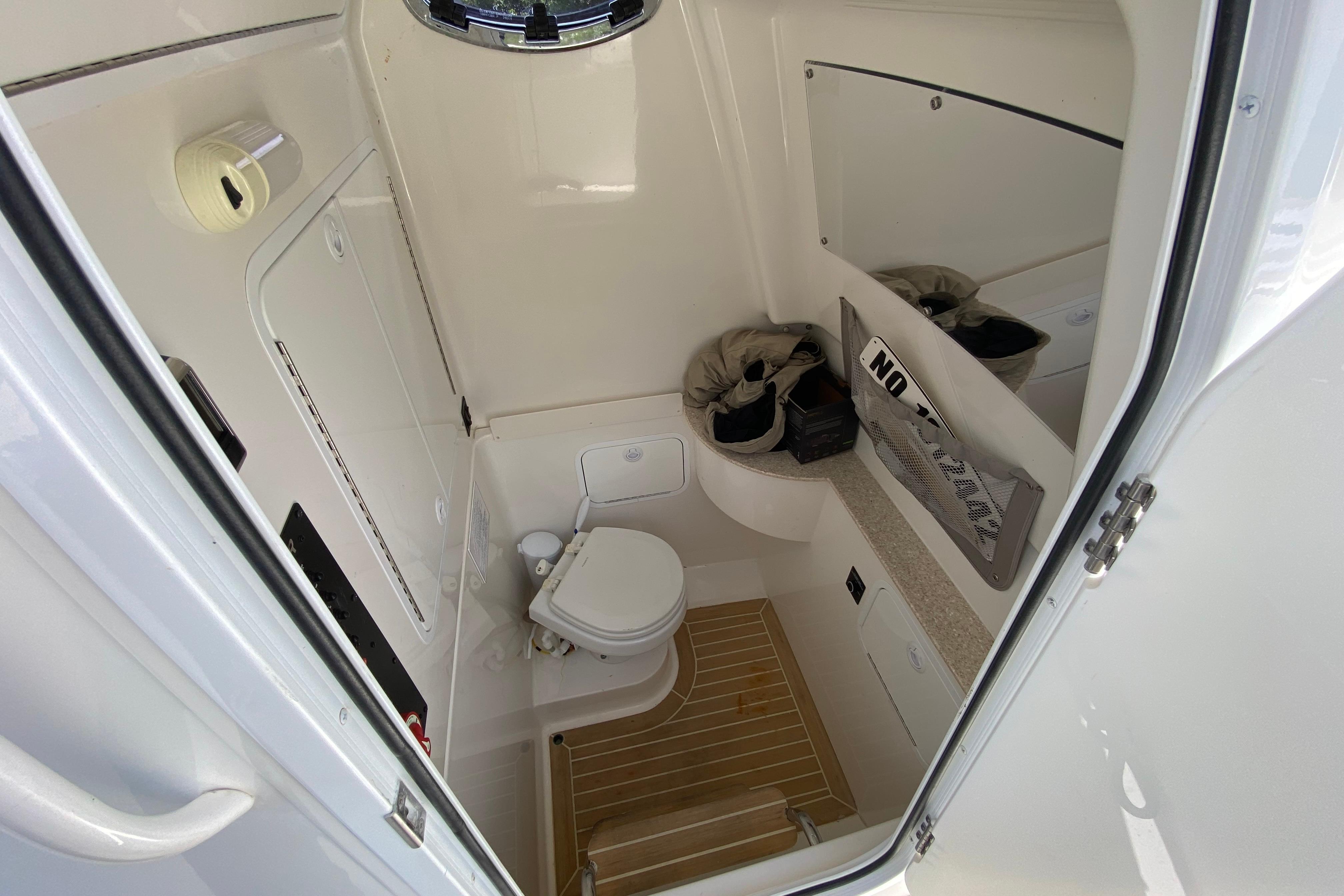 2021 Regulator 28 boat interior with compact bathroom, featuring toilet and storage.