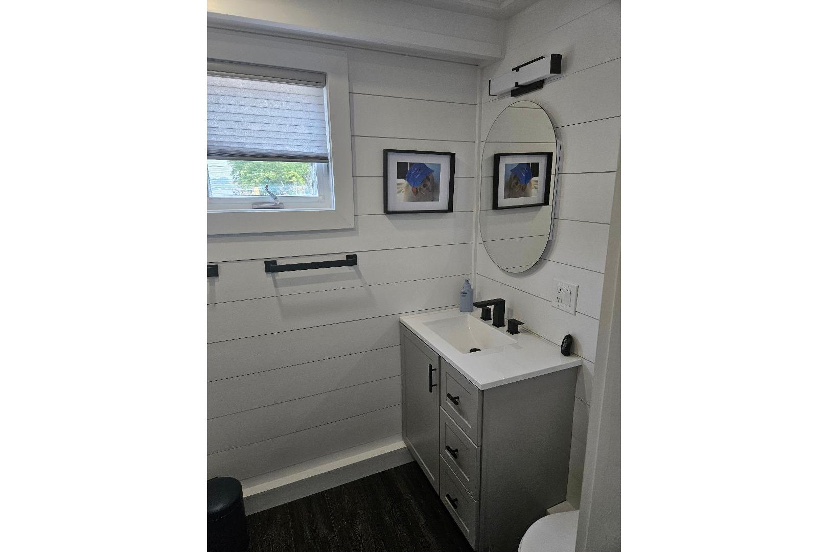 Modern bathroom in 2021 East Coast Houseboats Freedom 40, featuring sleek vanity and round mirror.