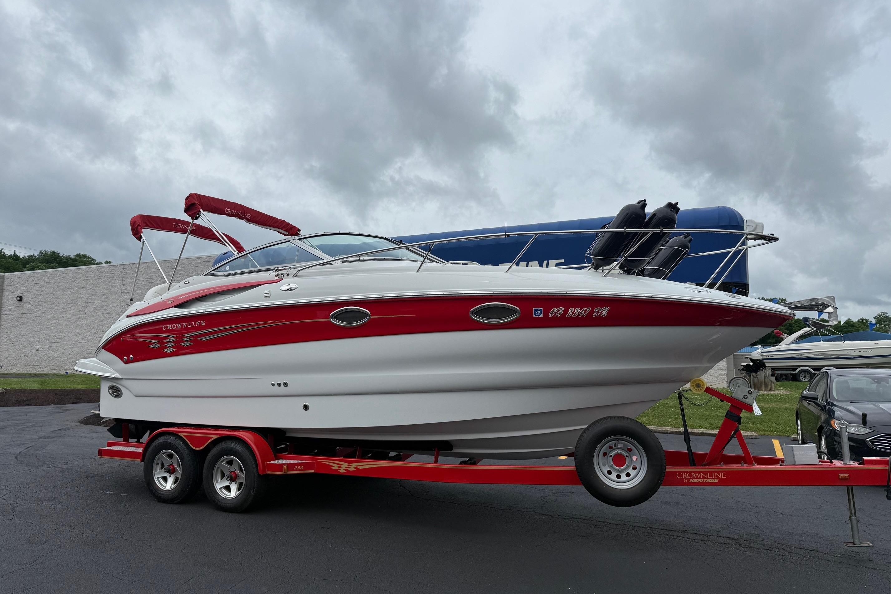 2005 Crownline 250 CR boat on trailer, red and white design, parked outdoors.