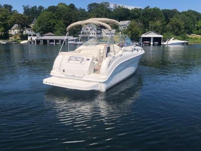 2003 Sea Ray 260 Sundancer boat on calm lake near shoreline homes.