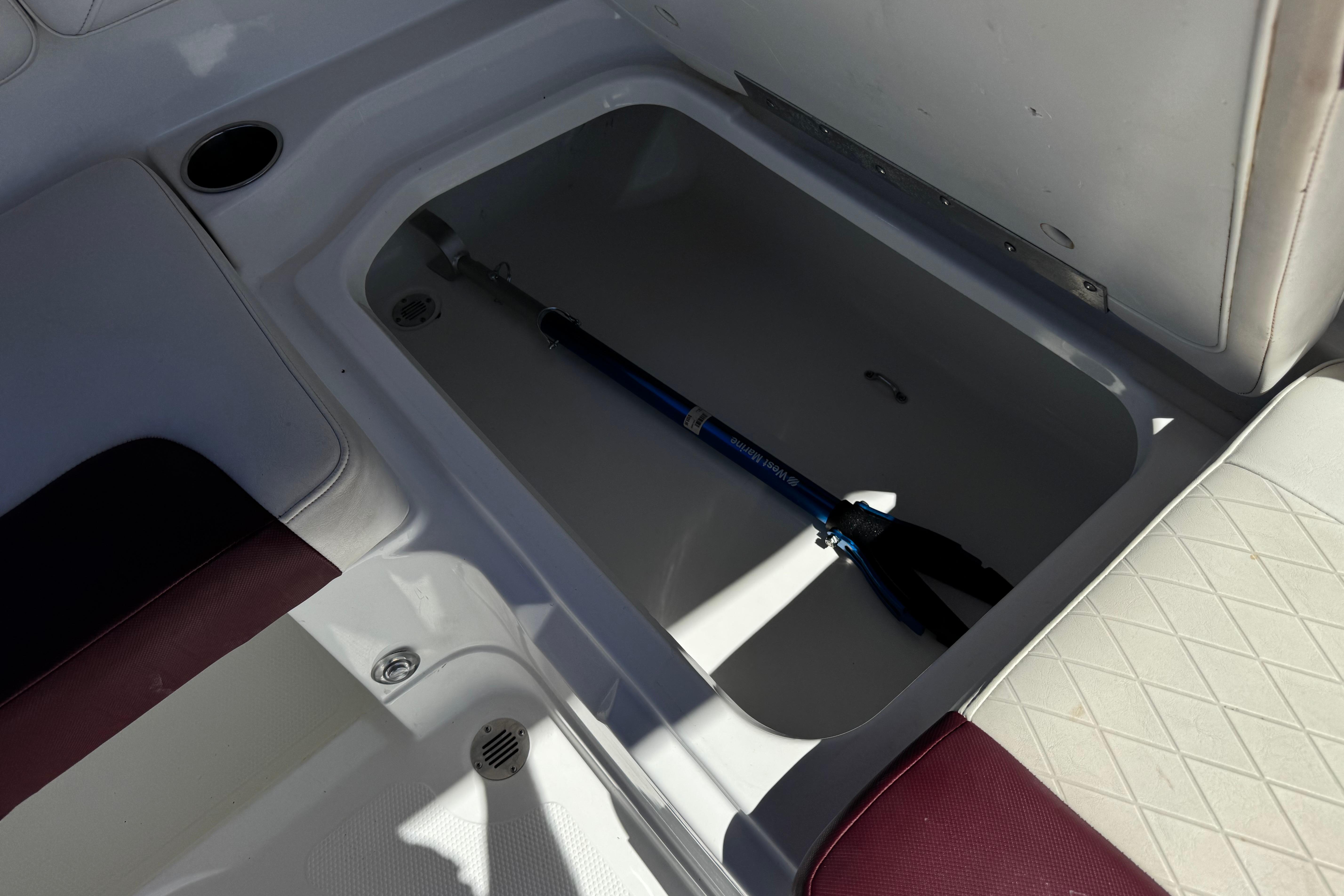Storage compartment in a 2017 Tahoe 2150 boat with a blue tool inside.
