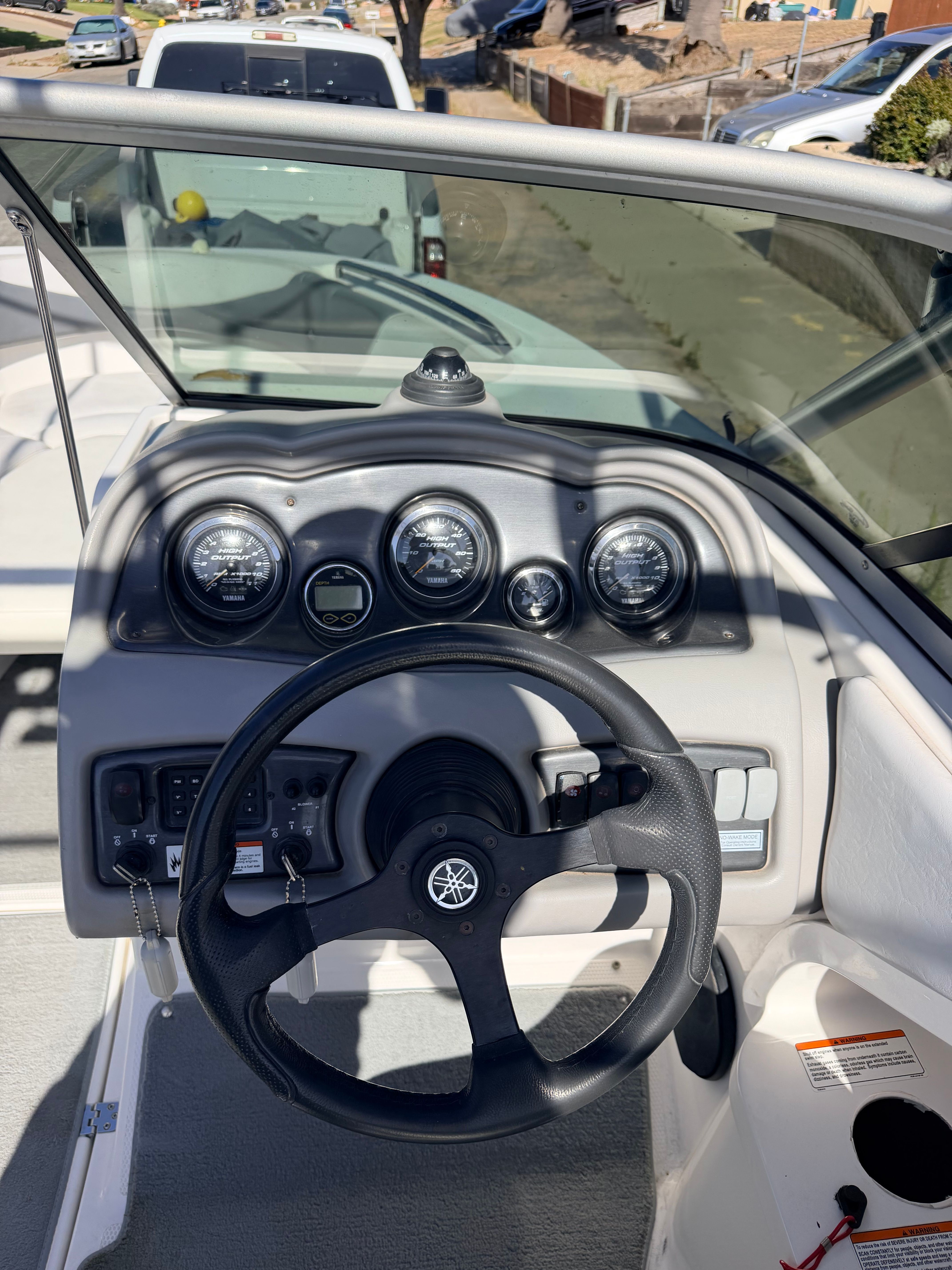 The image shows the cockpit of a 2005 Yamaha AR230 boat with a steering wheel and gauges.