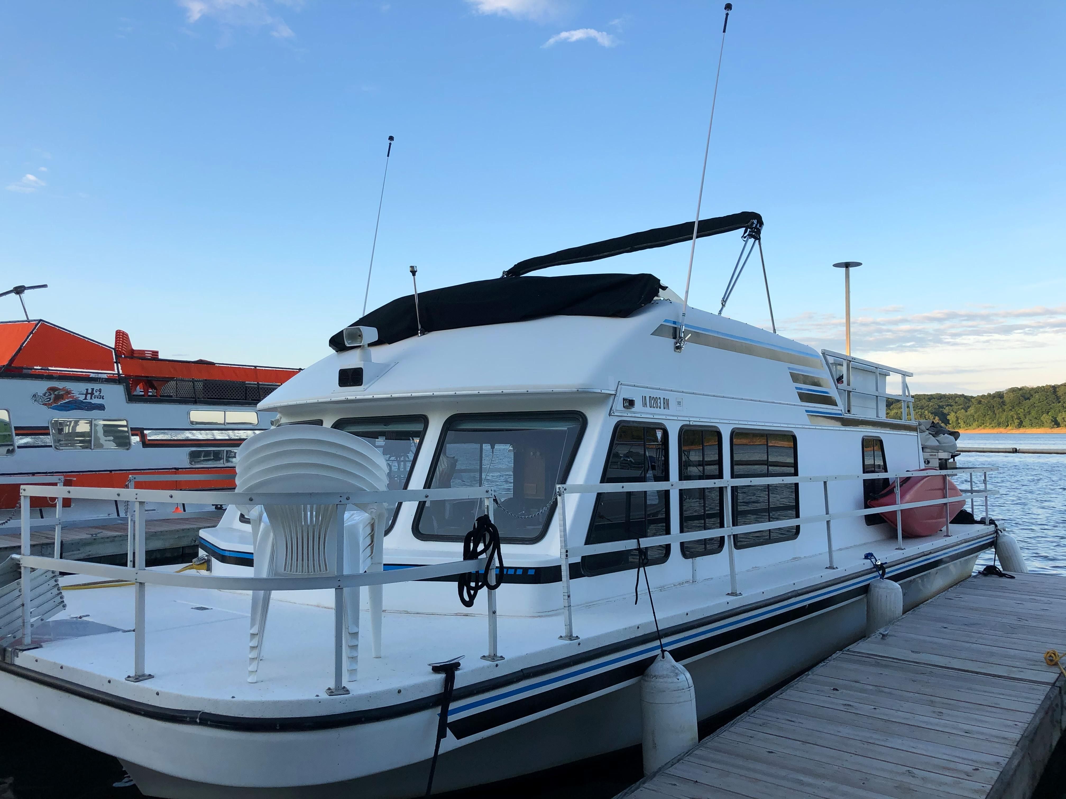 A 1993 Gibson Sport Series houseboat docked. It features a spacious deck.