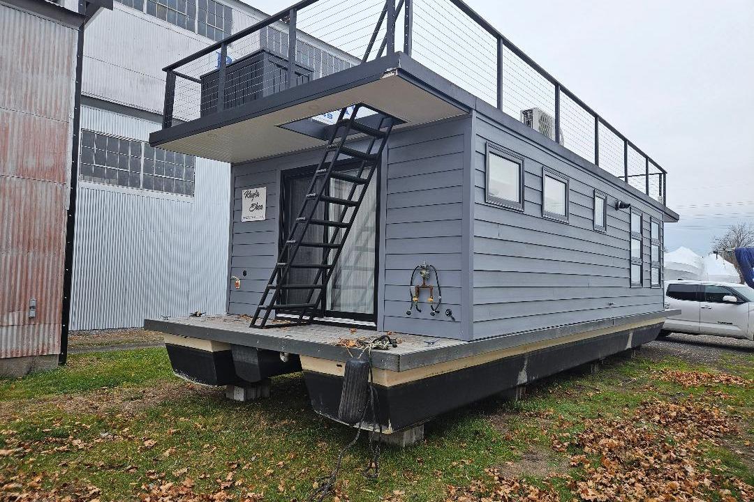 2021 East Coast Houseboats Freedom 40, modern design, docked on grass near industrial building.