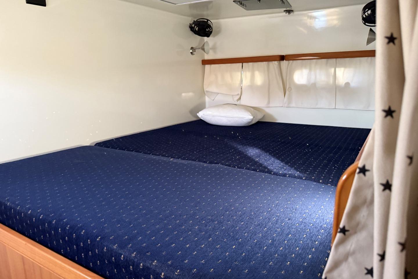 Interior cabin of 2006 Gunboat 48 with blue bedding and white curtains.
