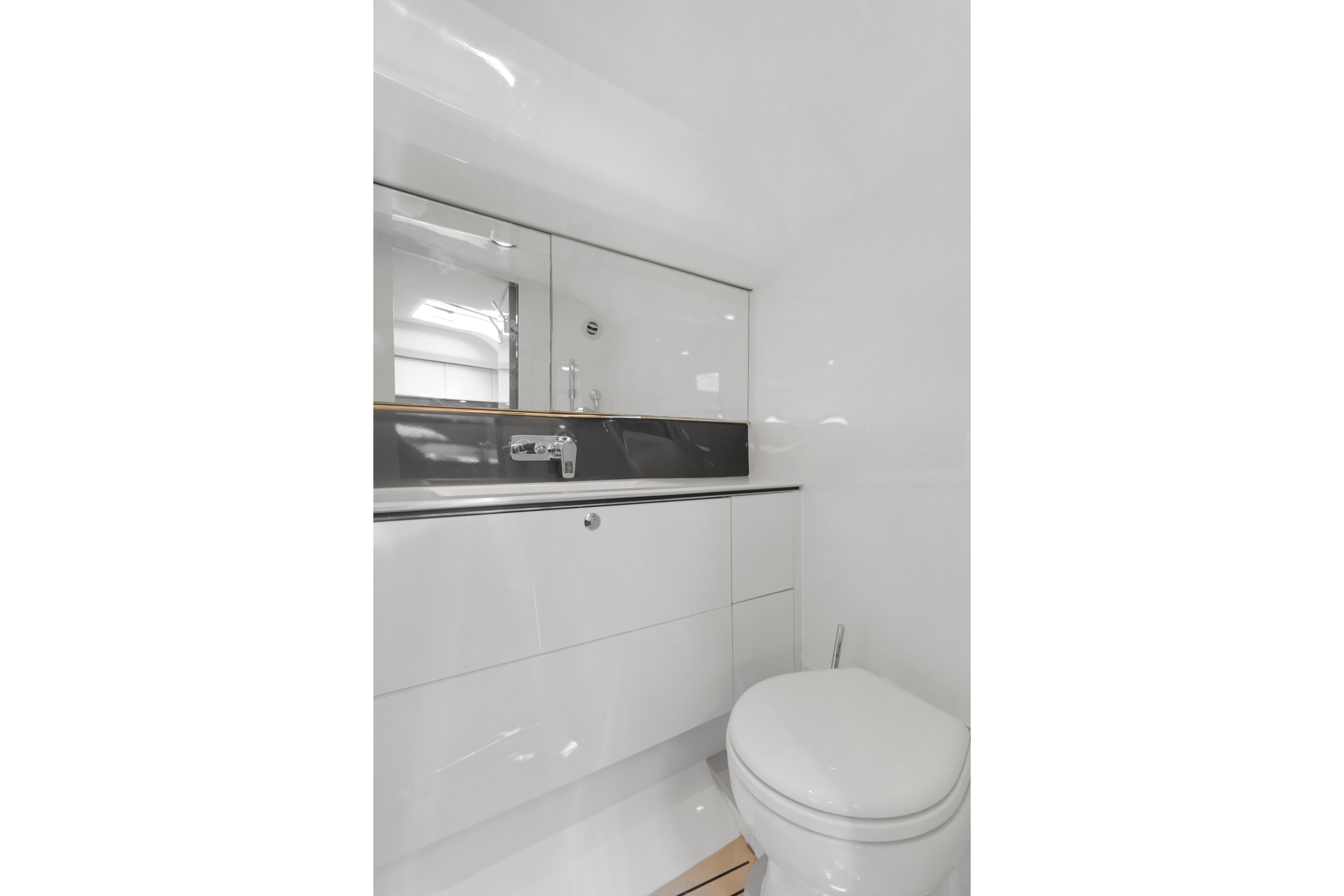 Modern yacht bathroom with sleek white fixtures, mirror, and sink. Princess R35, 2020 model.