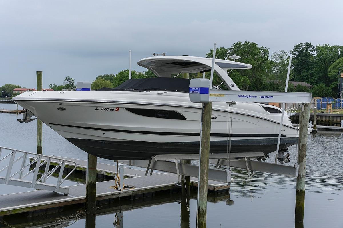2018 Sea Ray SLX 350 boat on lift at marina, surrounded by calm water and greenery.