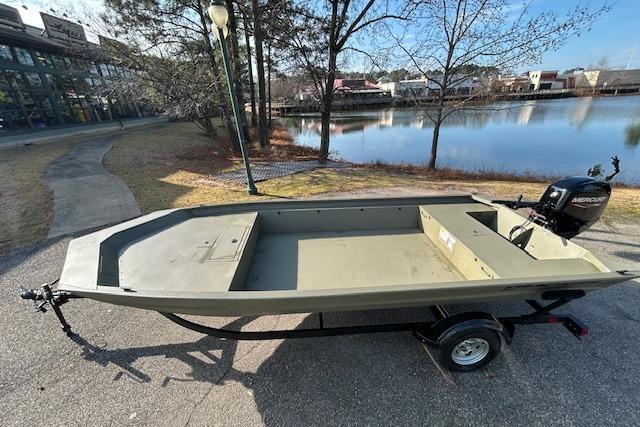 2026 Tracker Grizzly 1860 Utility boat on trailer by a lakeside path.