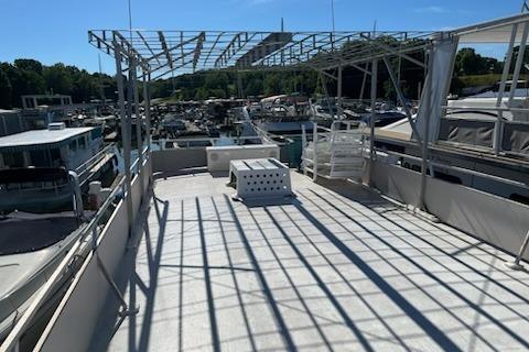 1994 PlayCraft 5215 boat deck with metal frame, docked at marina under clear blue sky.