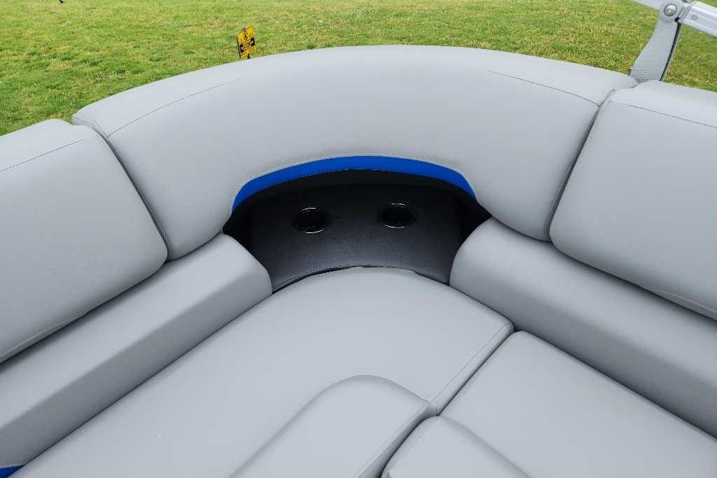 2026 Sun Tracker Party Barge 20 DLX, gray seating with cup holders, on grassy background.