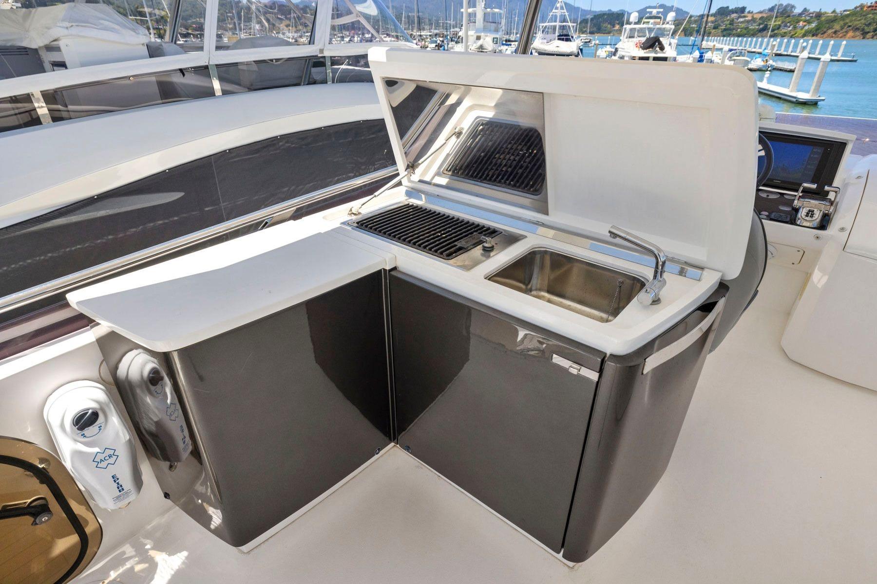 Outdoor kitchenette on 2015 Princess 60 Flybridge Motor Yacht with sink and grill.