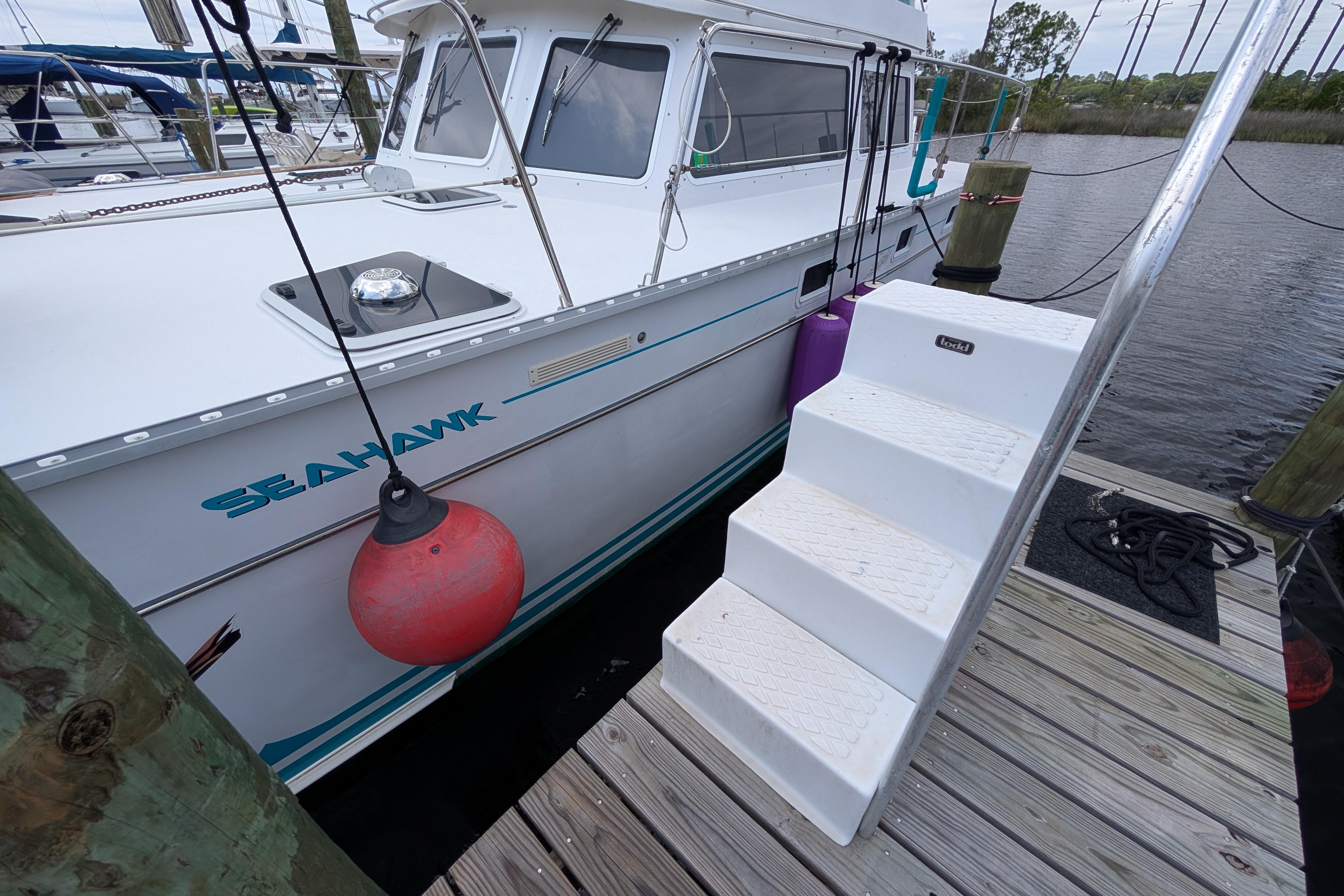 2004 PDQ 34 Powercat docked with steps and red buoy.