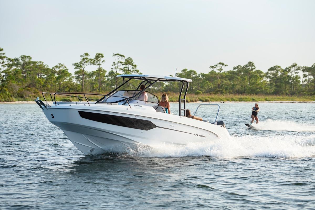 2026 Beneteau Flyer 8 SUNdeck cruising with wakeboarder on scenic waterway.