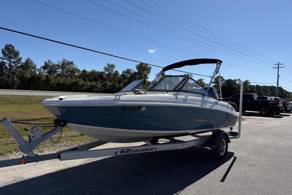 2024 Stingray 191 DC boat on trailer, parked outdoors under clear blue sky.
