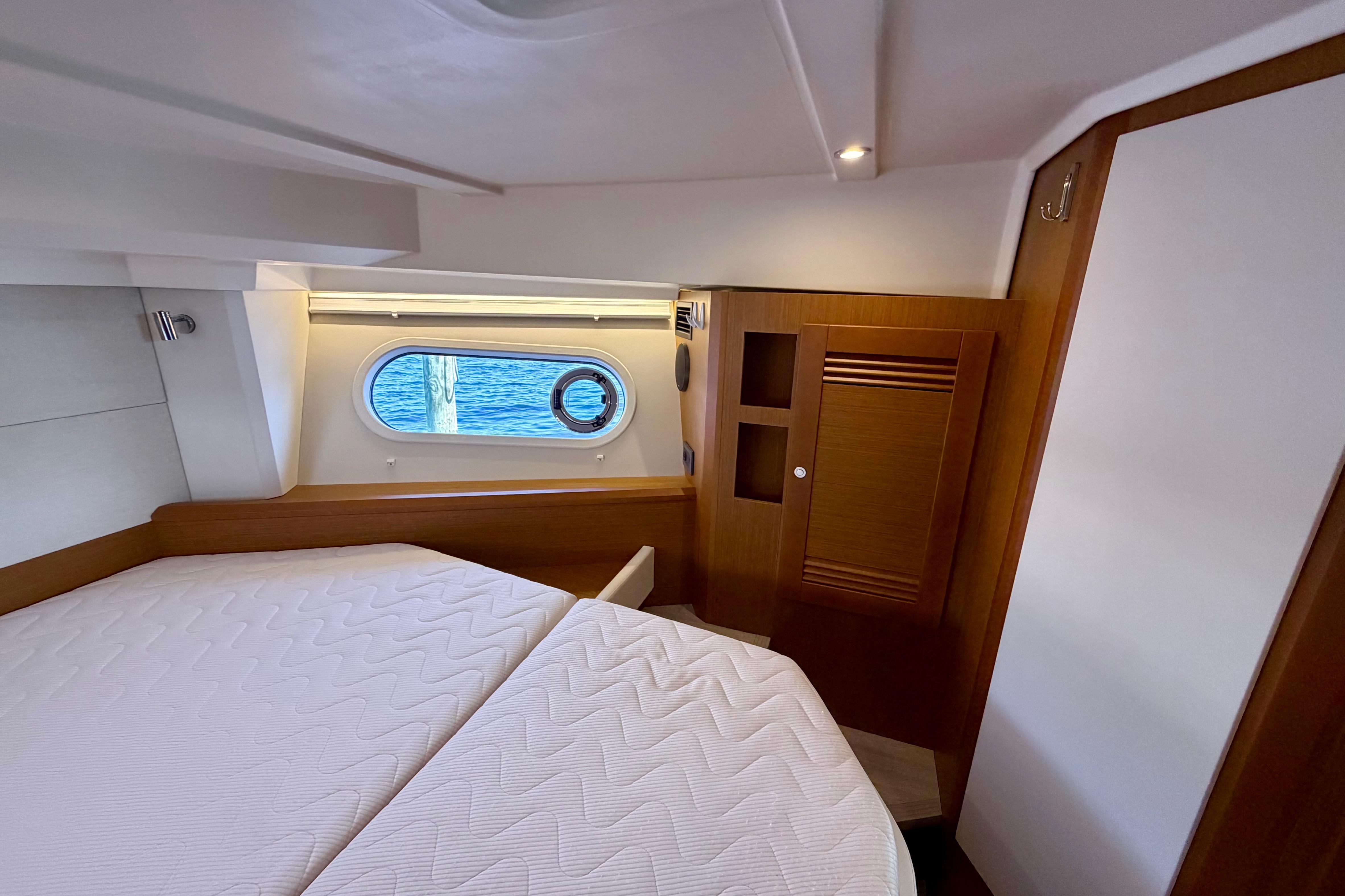 2025 Beneteau Swift Trawler 41 Fly cabin interior with bed and porthole view.