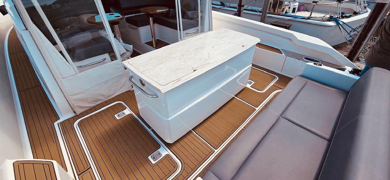 The image shows the deck of a 2017 Tiara Yachts Q44 with elegant wood flooring and a table.