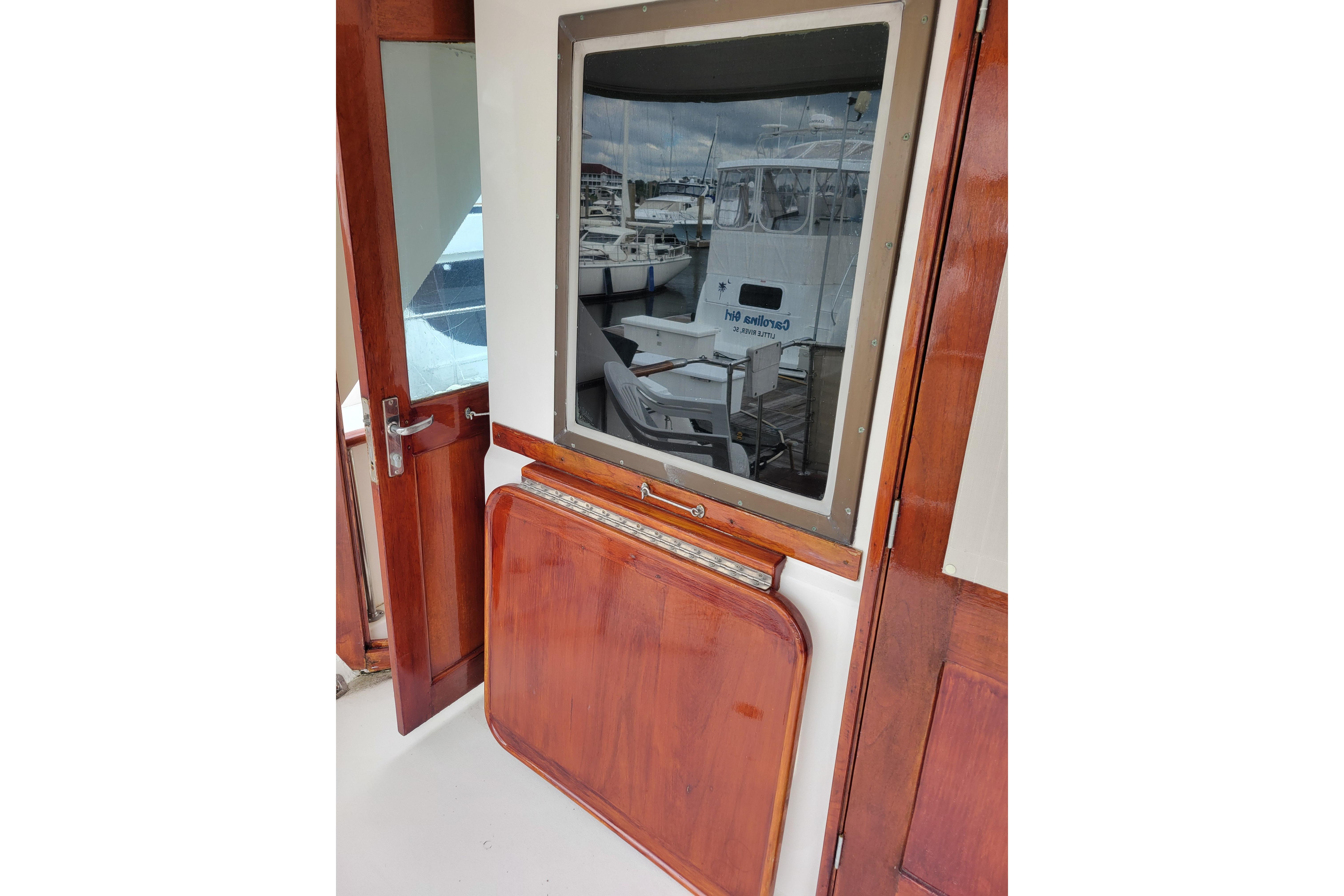 1980 Hatteras 53 Yacht Fisherman interior with wooden doors and window reflection.