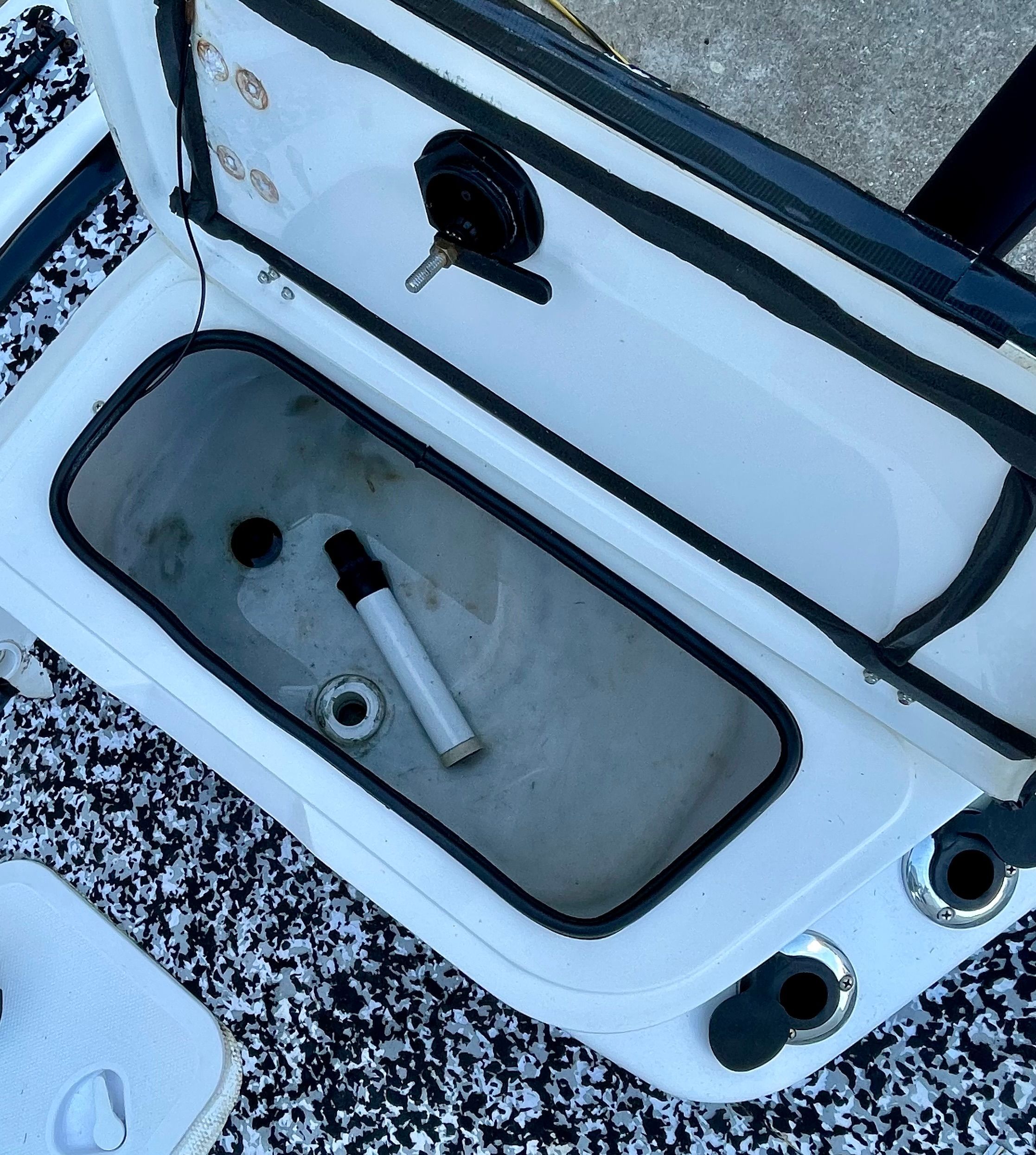 An open storage compartment on a 2006 Mako 2101 Inshore boat with a pipe inside.