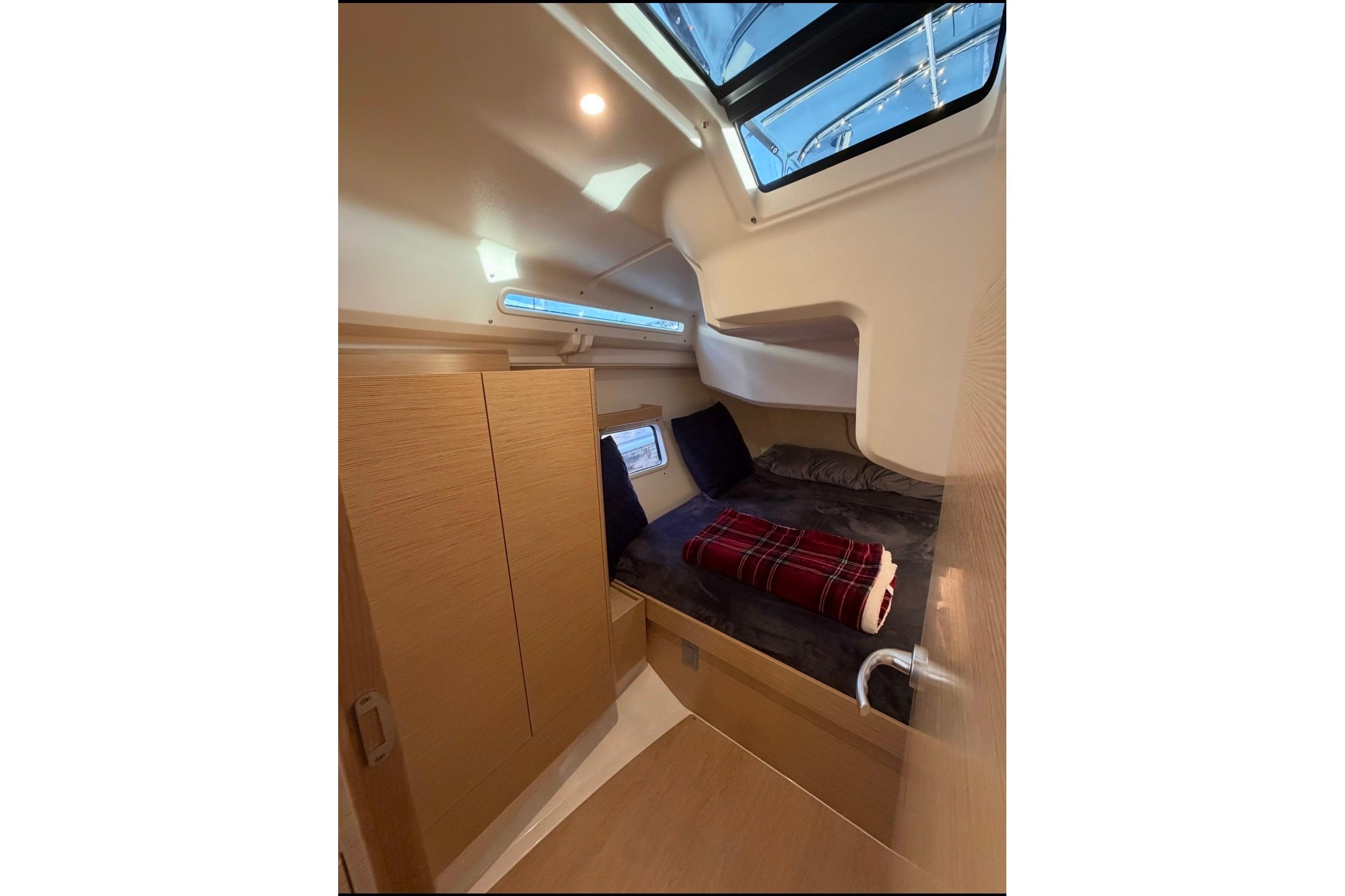 Cozy cabin interior of 2022 Hanse 418 yacht with skylight and plaid blanket.