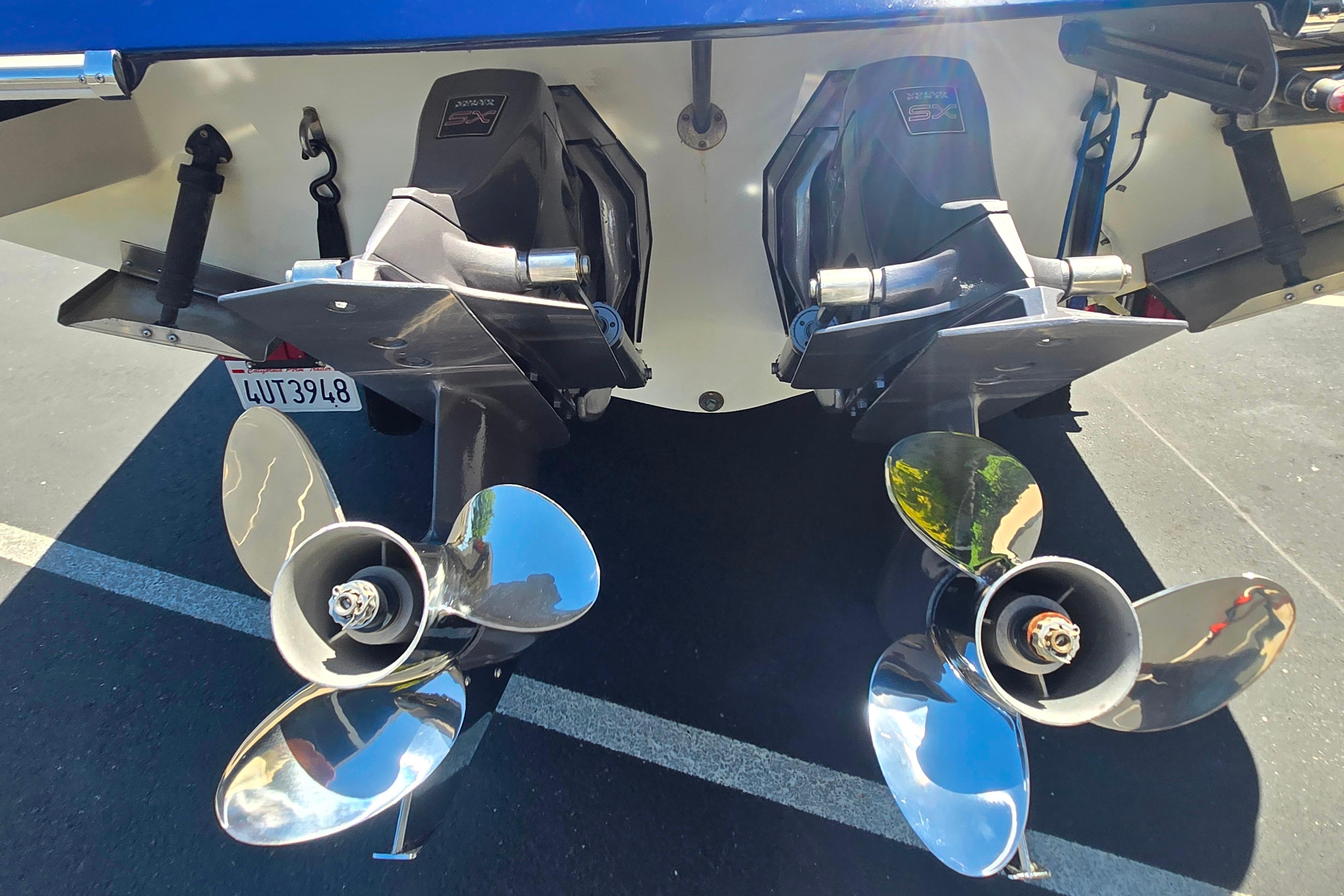 Dual propellers of a 2002 Chris-Craft Launch 28 GT I/O boat in a parking lot.