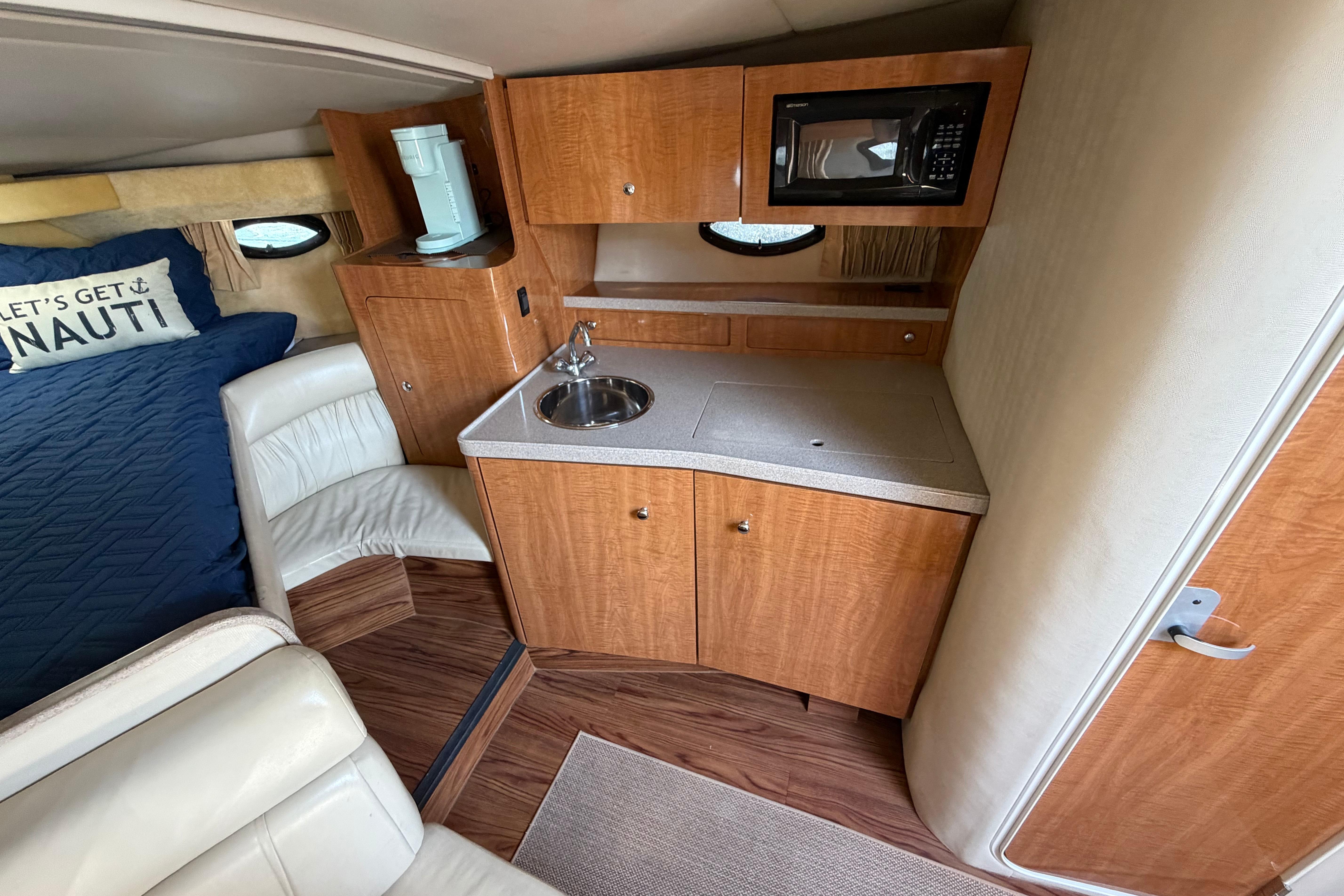 2003 Regal Commodore 3260 cabin interior with kitchenette, sink, microwave, and cozy seating area.