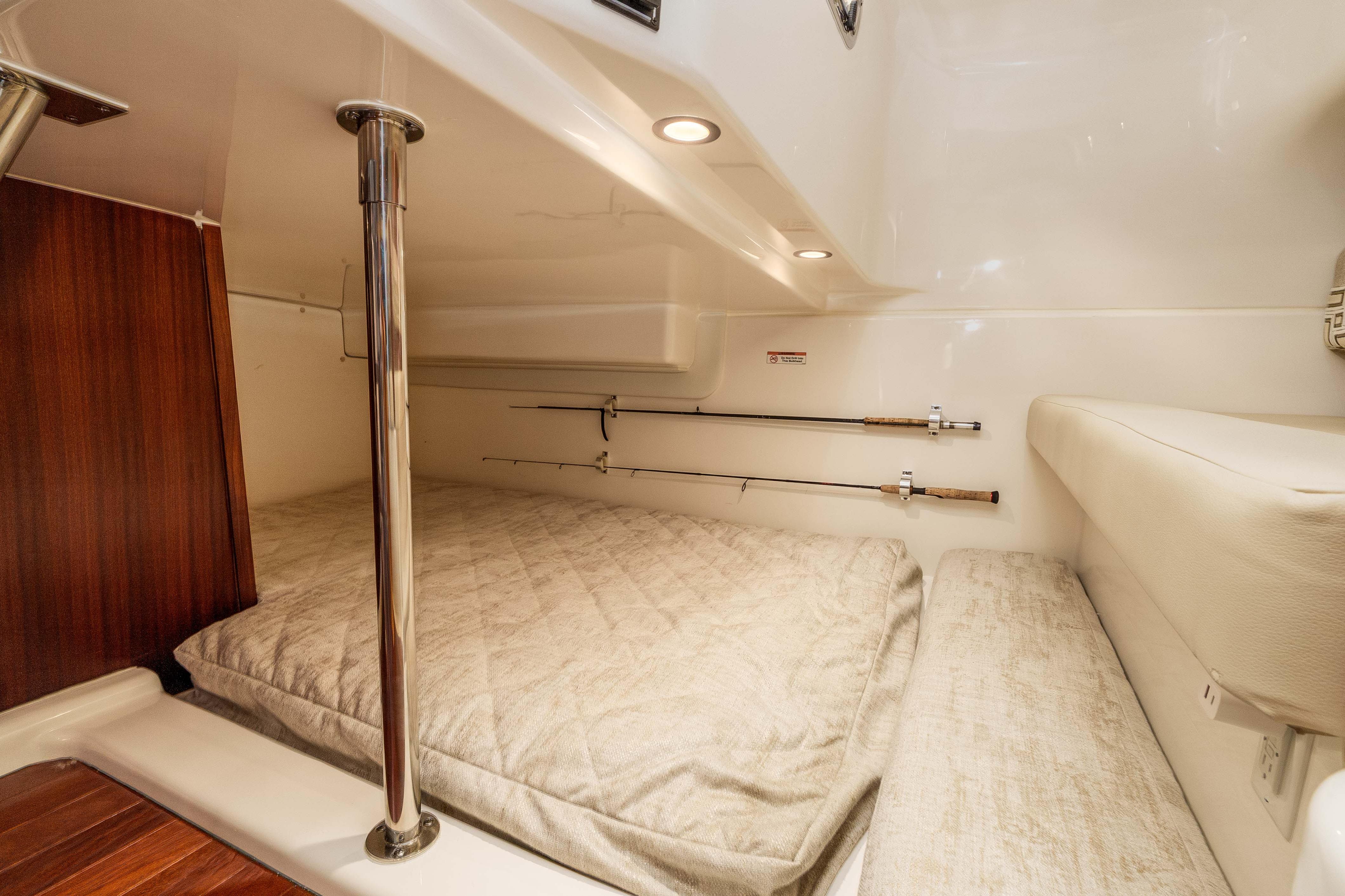 2022 Pursuit OS 385 Offshore cabin interior with fishing rods and cozy bedding.