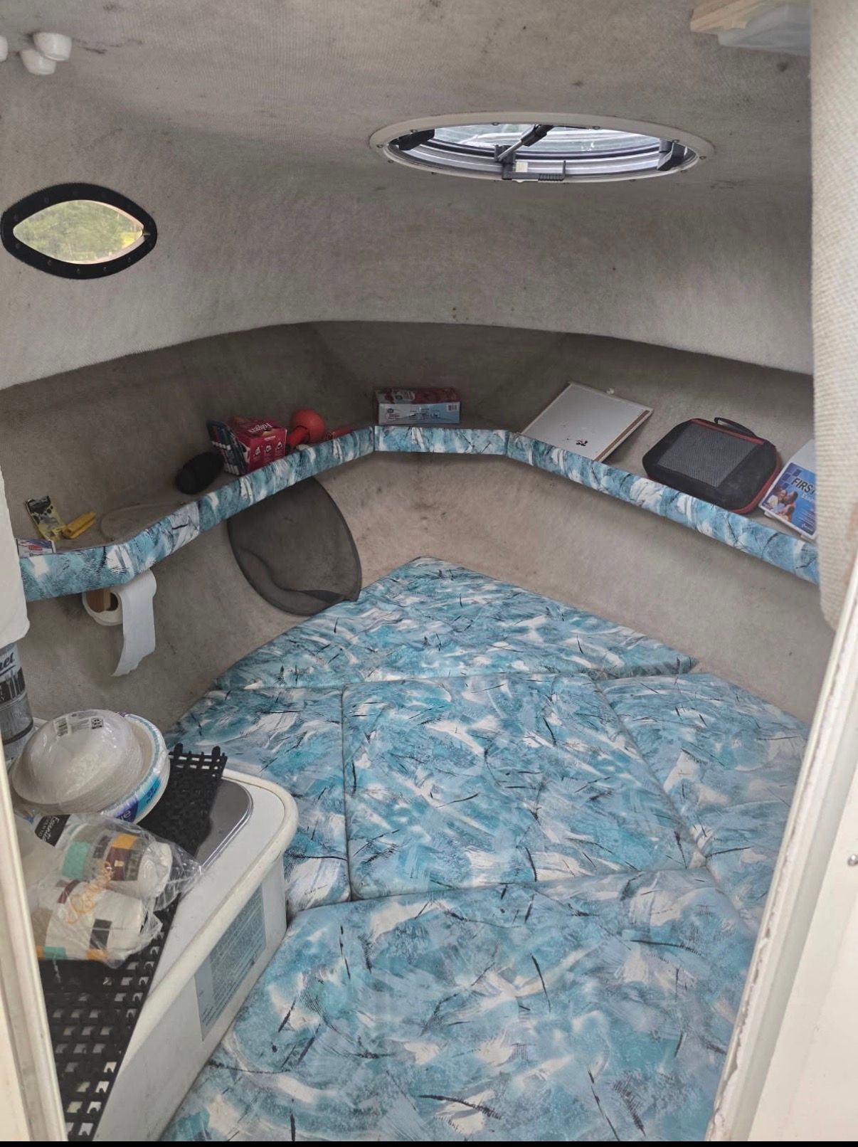 Interior of a 1999 Seaswirl Striper 2100 with blue and white bedding and storage shelves.