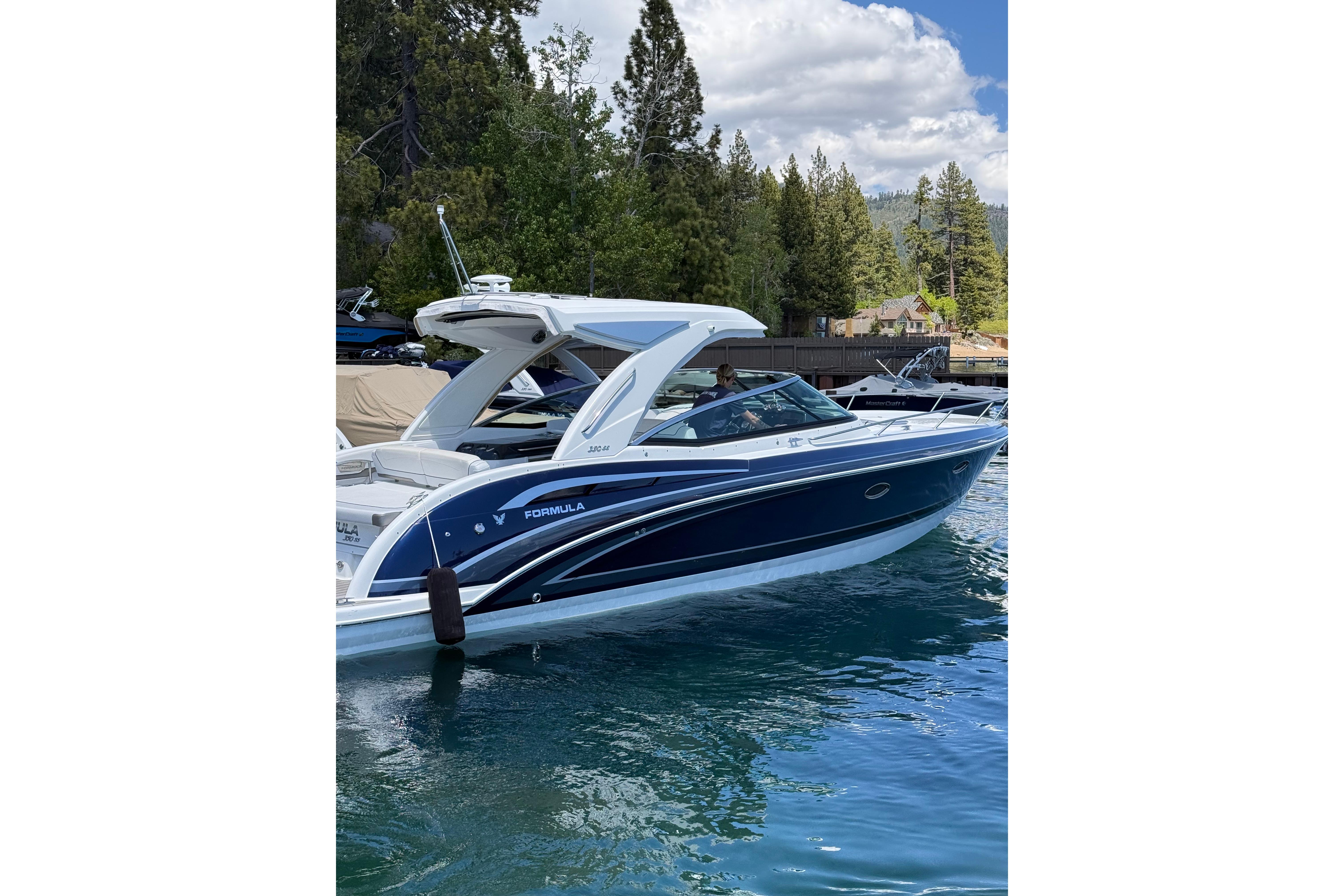 2021 Formula 350 Sun Sport boat docked on a serene lake with lush forest backdrop.