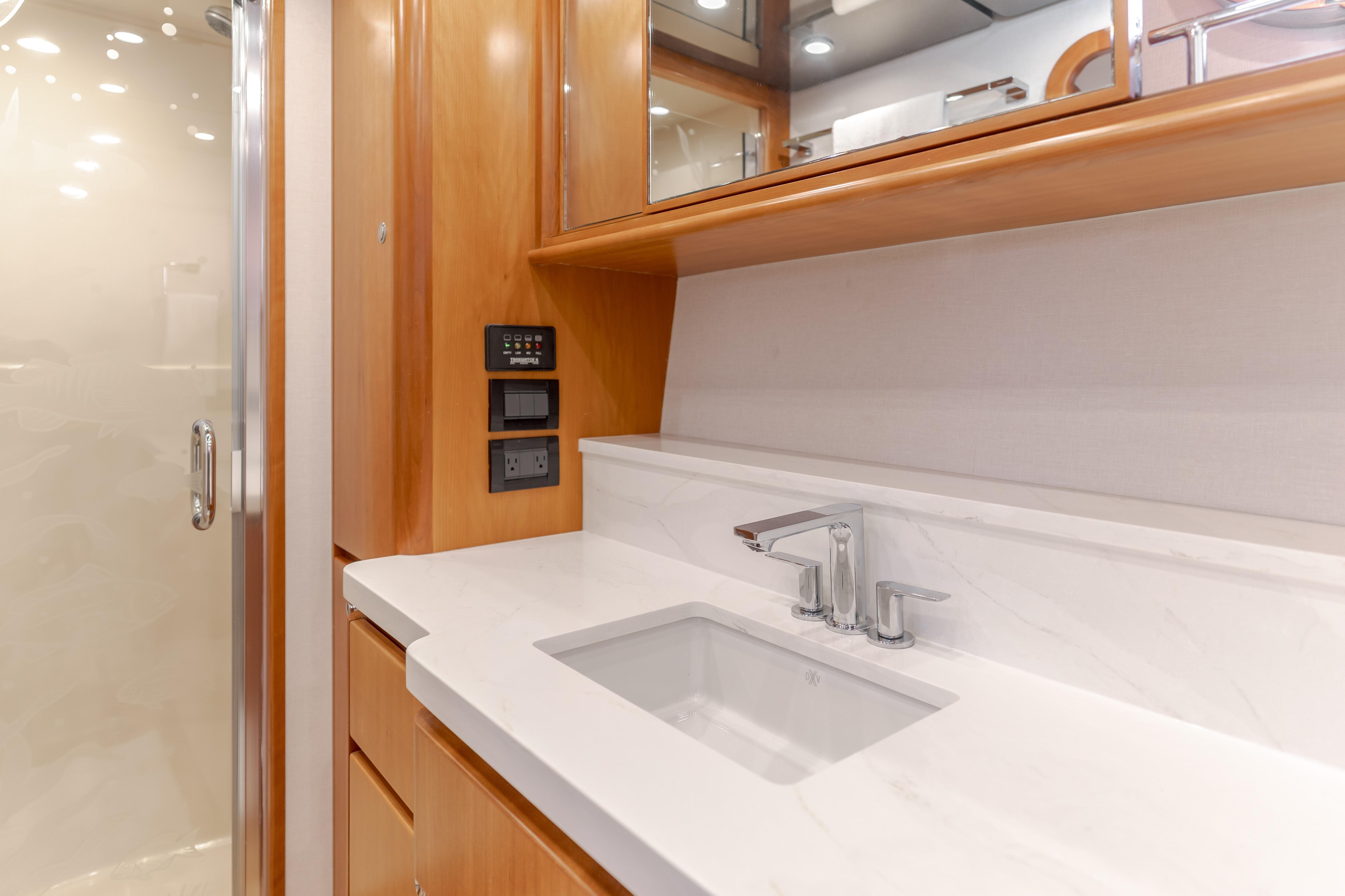 Luxurious bathroom sink area in 2006 West Bay 64 yacht, featuring modern fixtures and wood cabinetry.