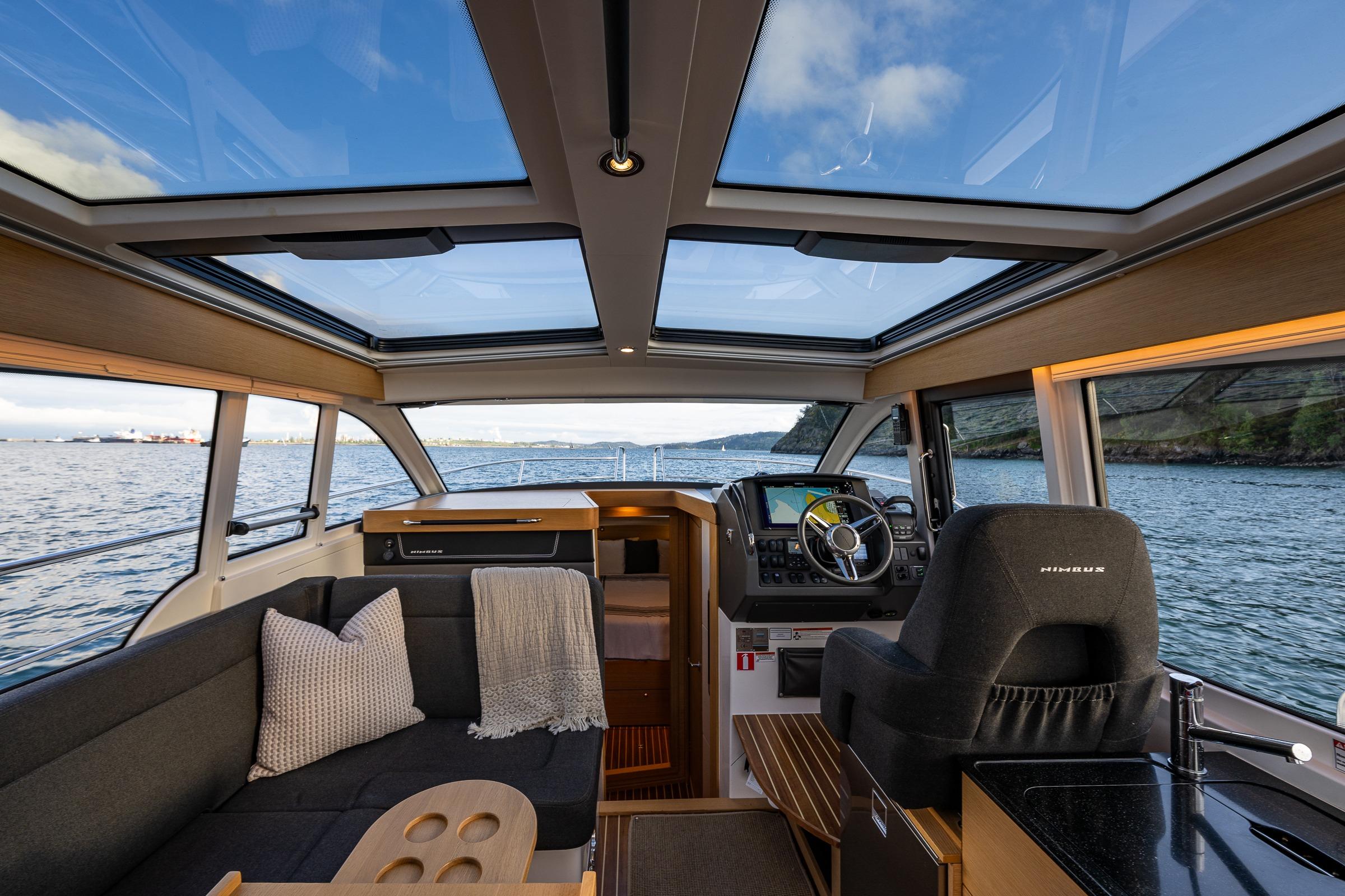 Interior of 2022 Nimbus 365 Coupe boat with panoramic windows and modern helm.
