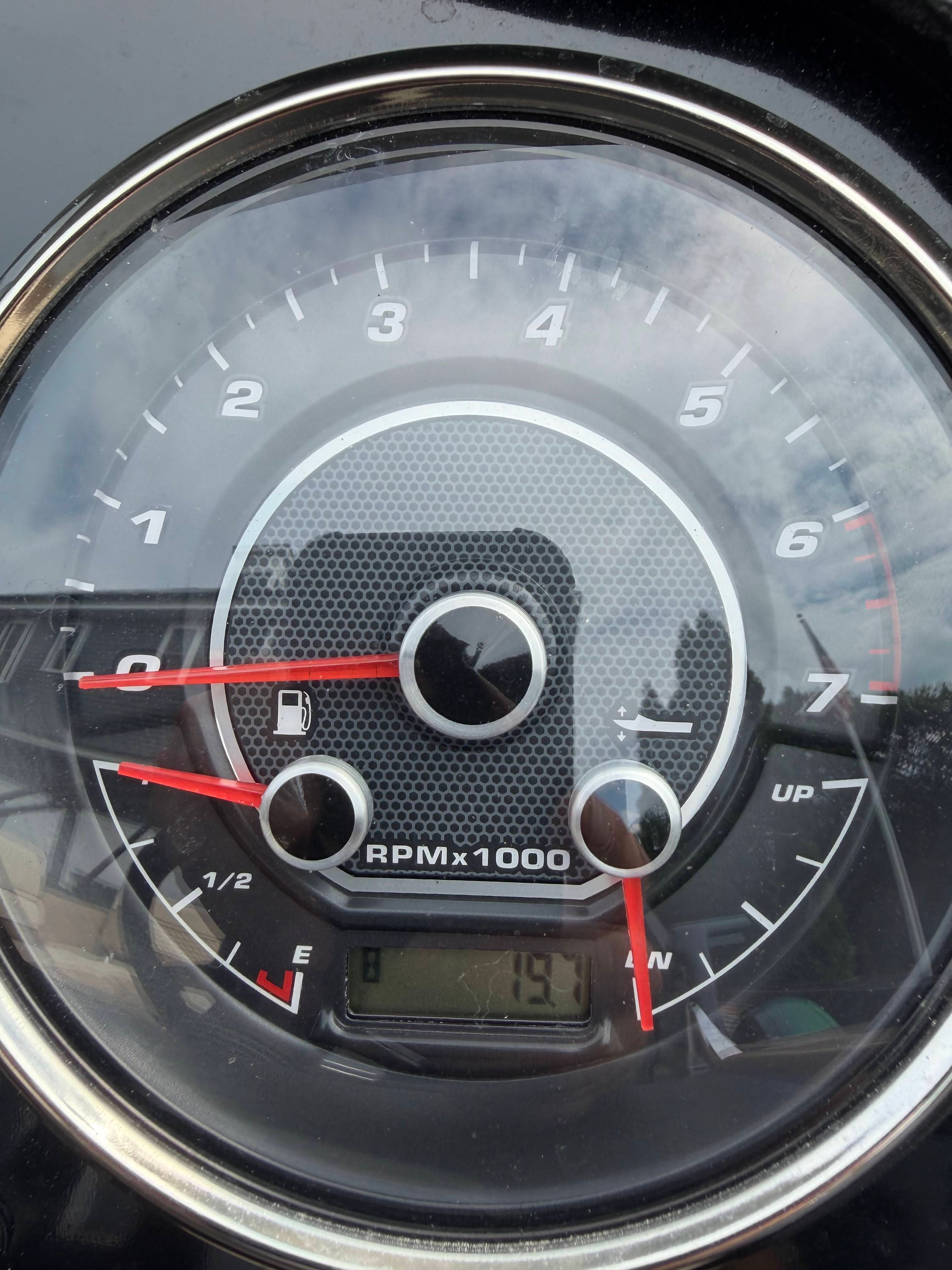 Close-up of a tachometer with red needles and digital display.