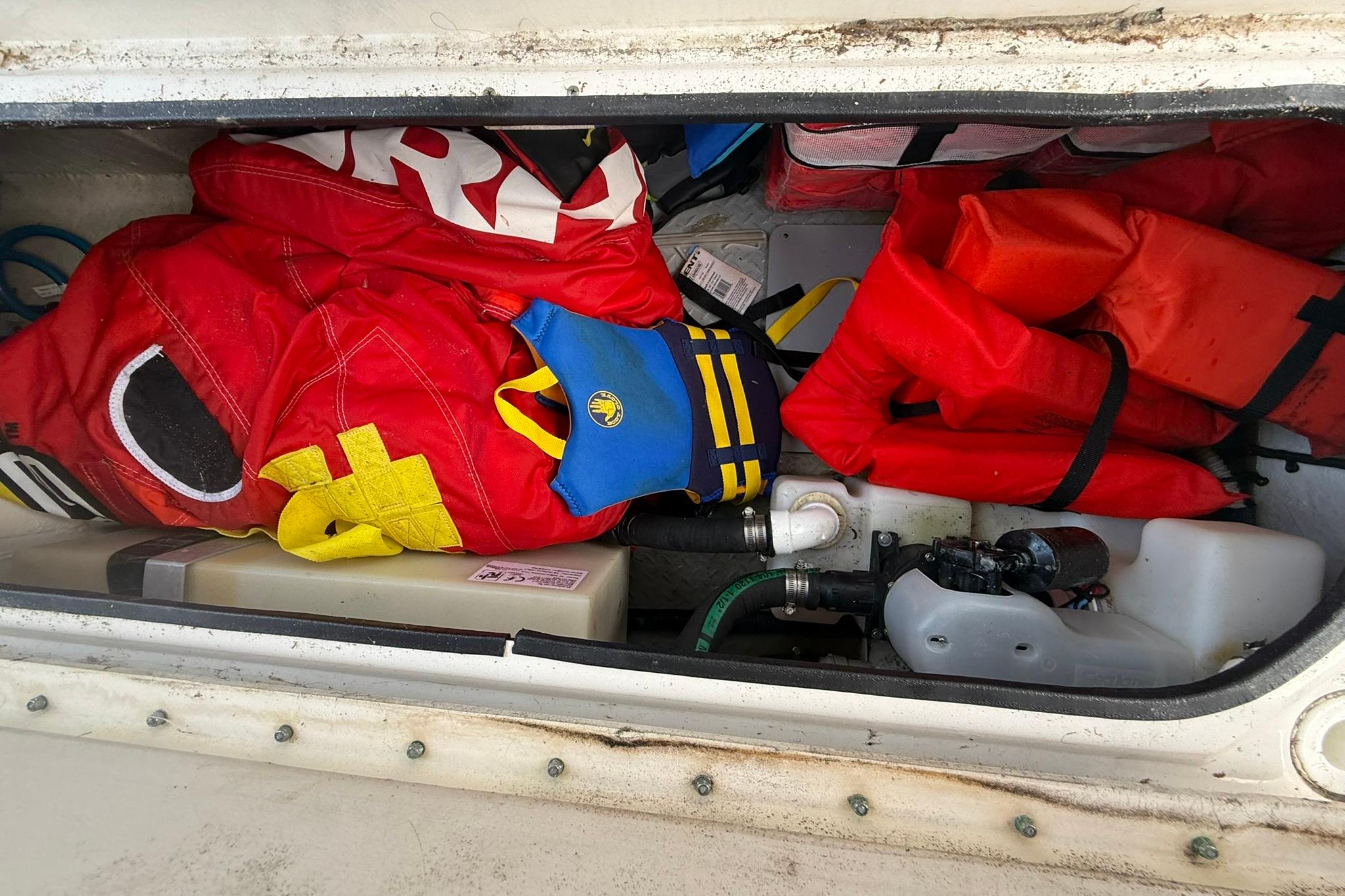 Storage compartment of a 2005 Sea Ray 290 SLX with life jackets and equipment.