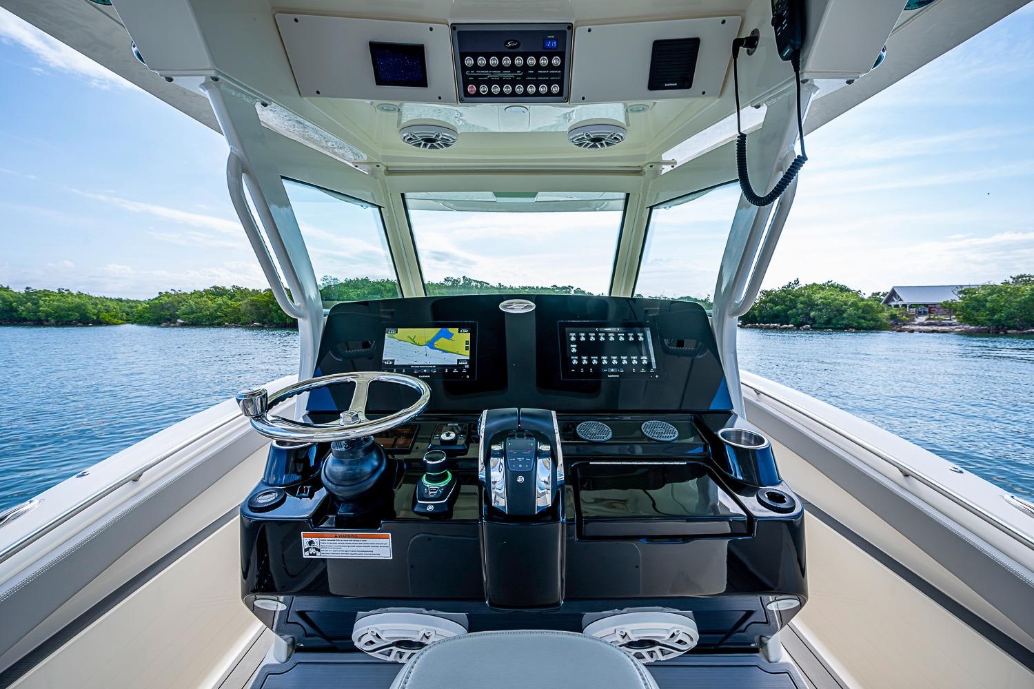 Helm of 2021 Scout 330 LXF boat with modern controls and scenic water view.