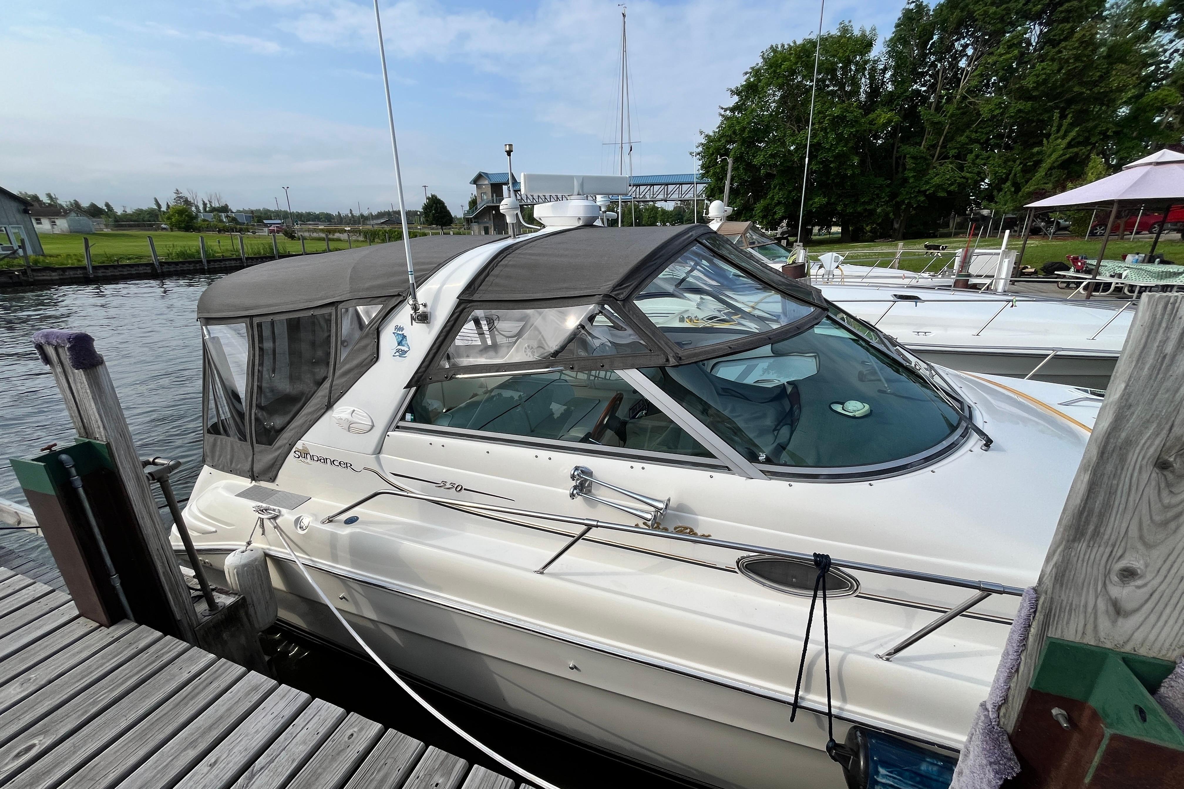 1995 Sea Ray Sundancer 330 docked at a marina, featuring a sleek design and covered cockpit.