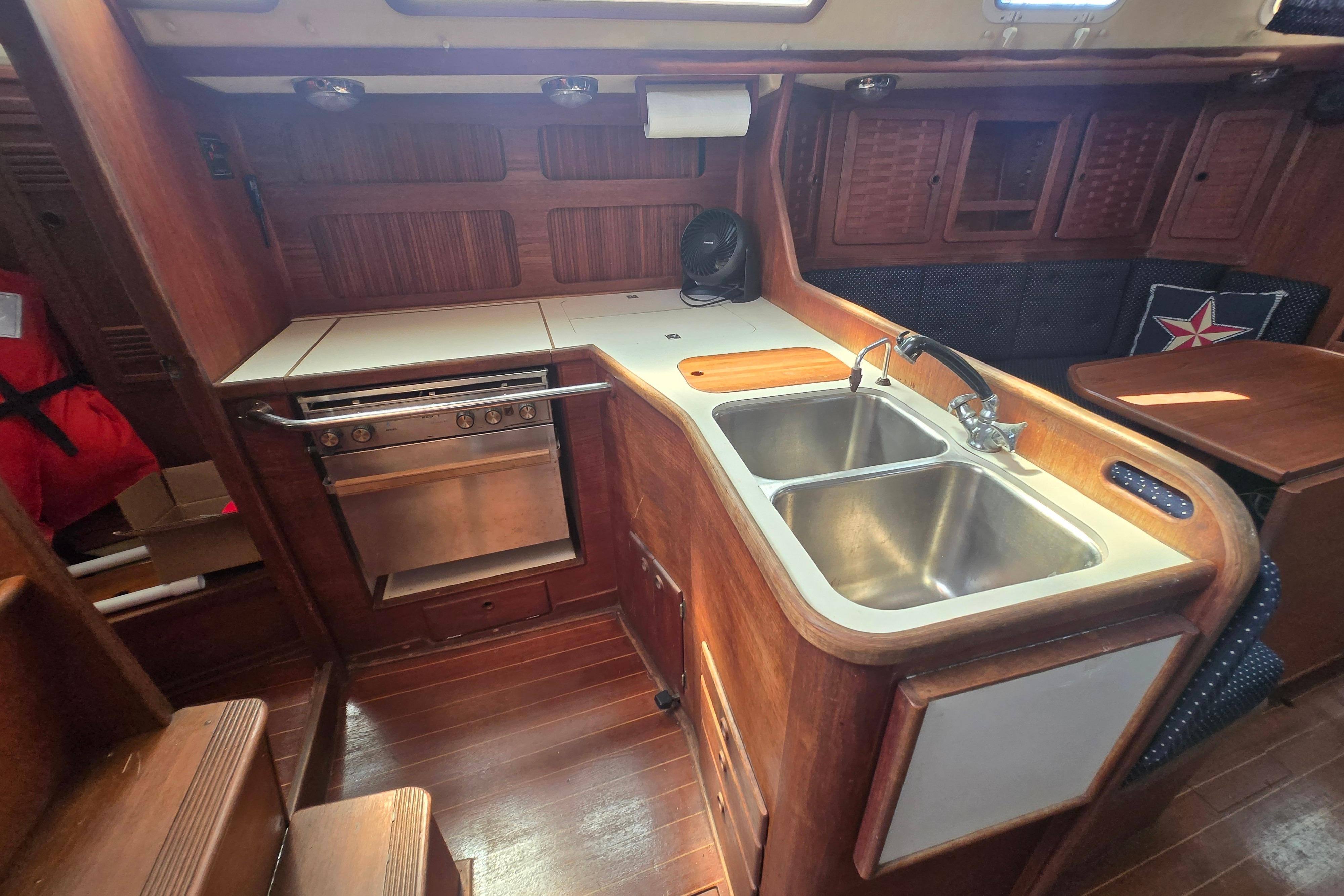 1988 Sabre 38 yacht interior kitchen with wooden cabinetry, dual sink, and stove.