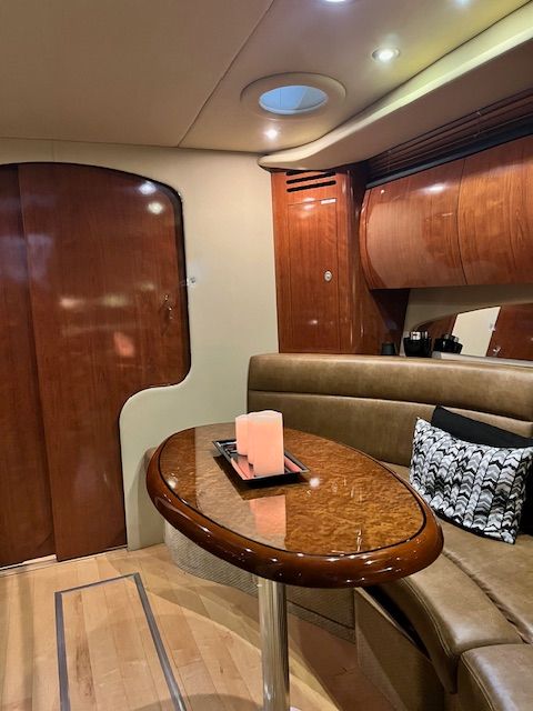 Interior of a 2005 Sea Ray Sundancer yacht with wooden table and sofa.
