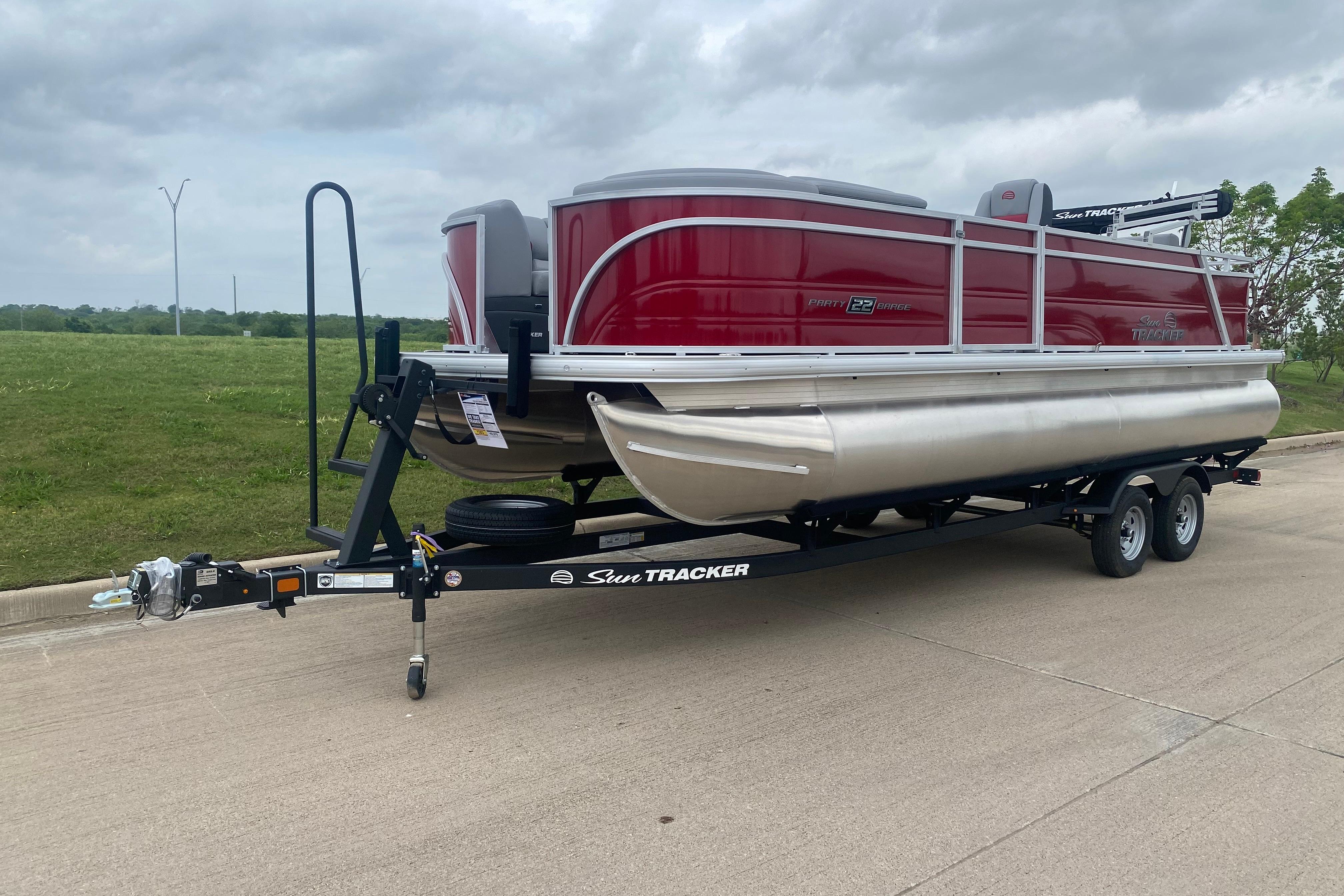 2026 Sun Tracker Party Barge 22 RF DLX pontoon boat on trailer, parked outdoors.