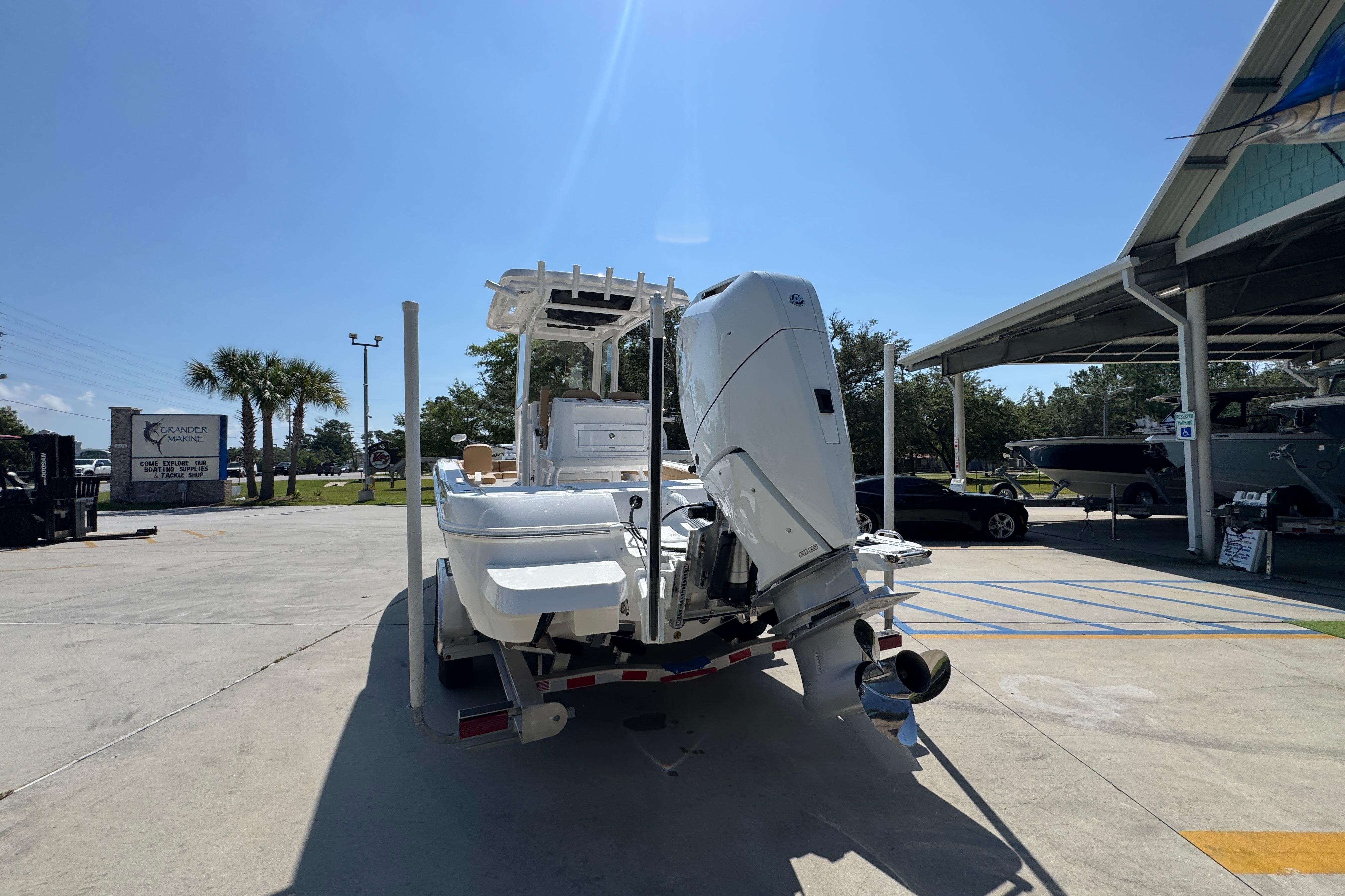2027 Caymas 26 HB boat with outboard motor on trailer in sunny marina.