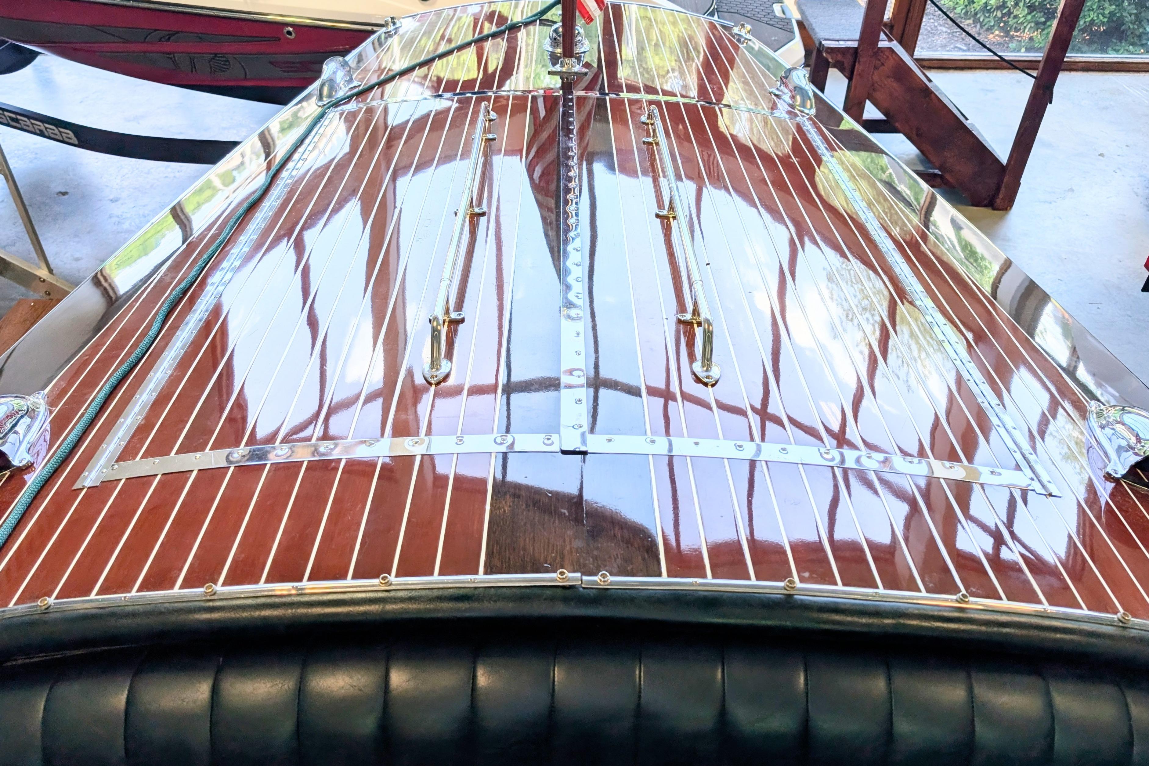Polished wooden deck of a 2001 Hacker-Craft 24 Dual Console boat in a garage.