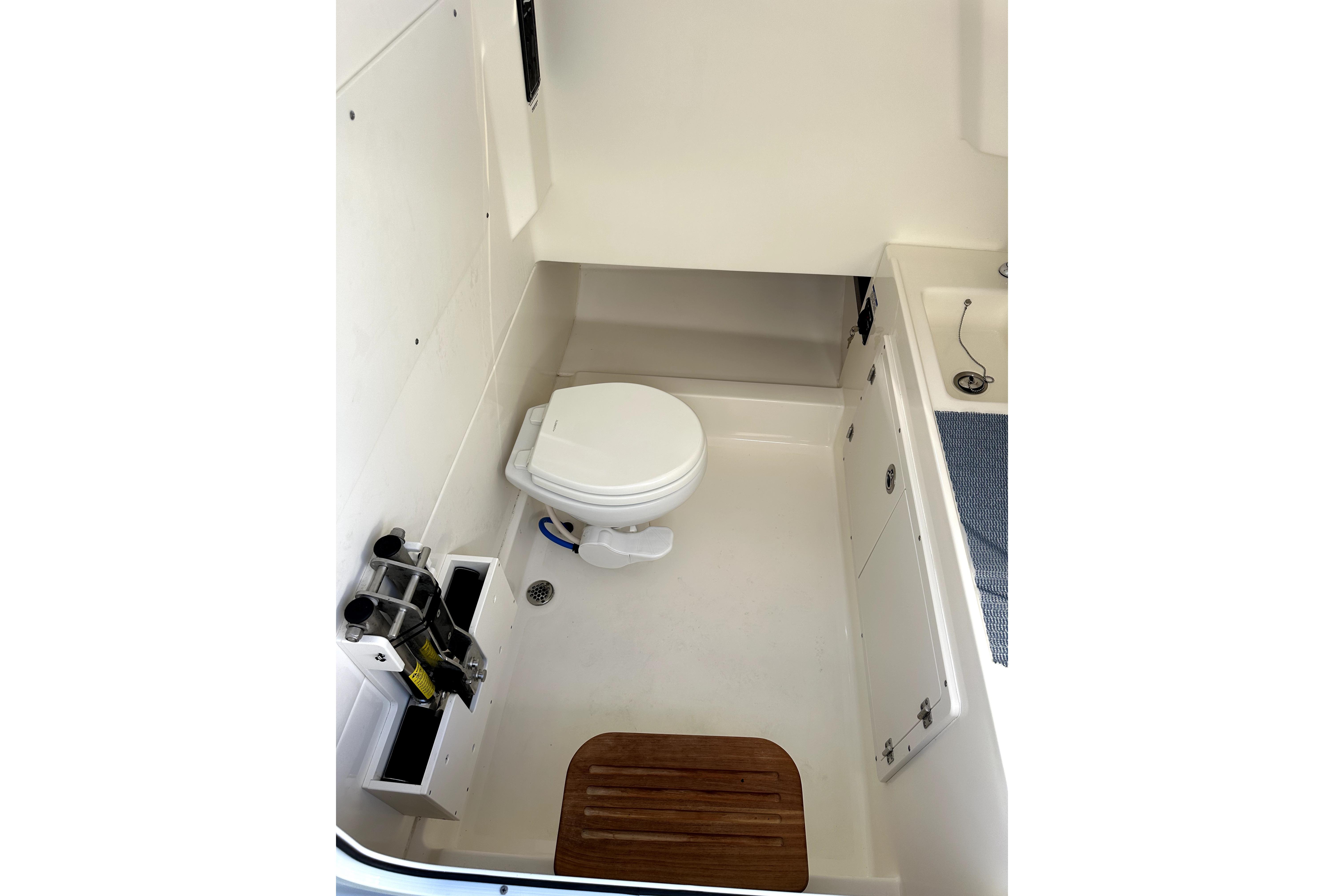 2023 Boston Whaler OUTRAGE boat interior with toilet and storage compartments.