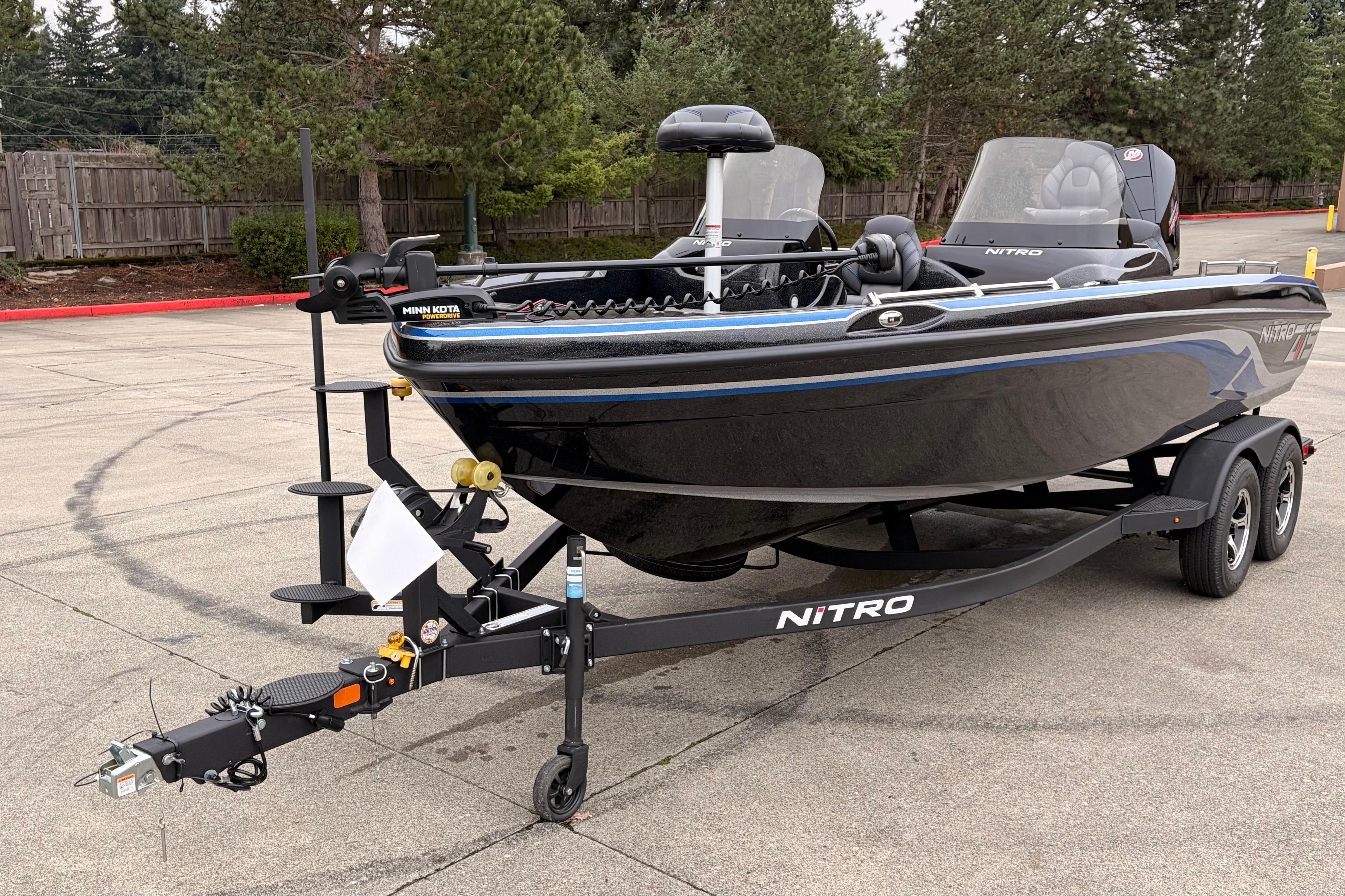 2025 Nitro ZV19 boat on trailer in parking lot, surrounded by trees.
